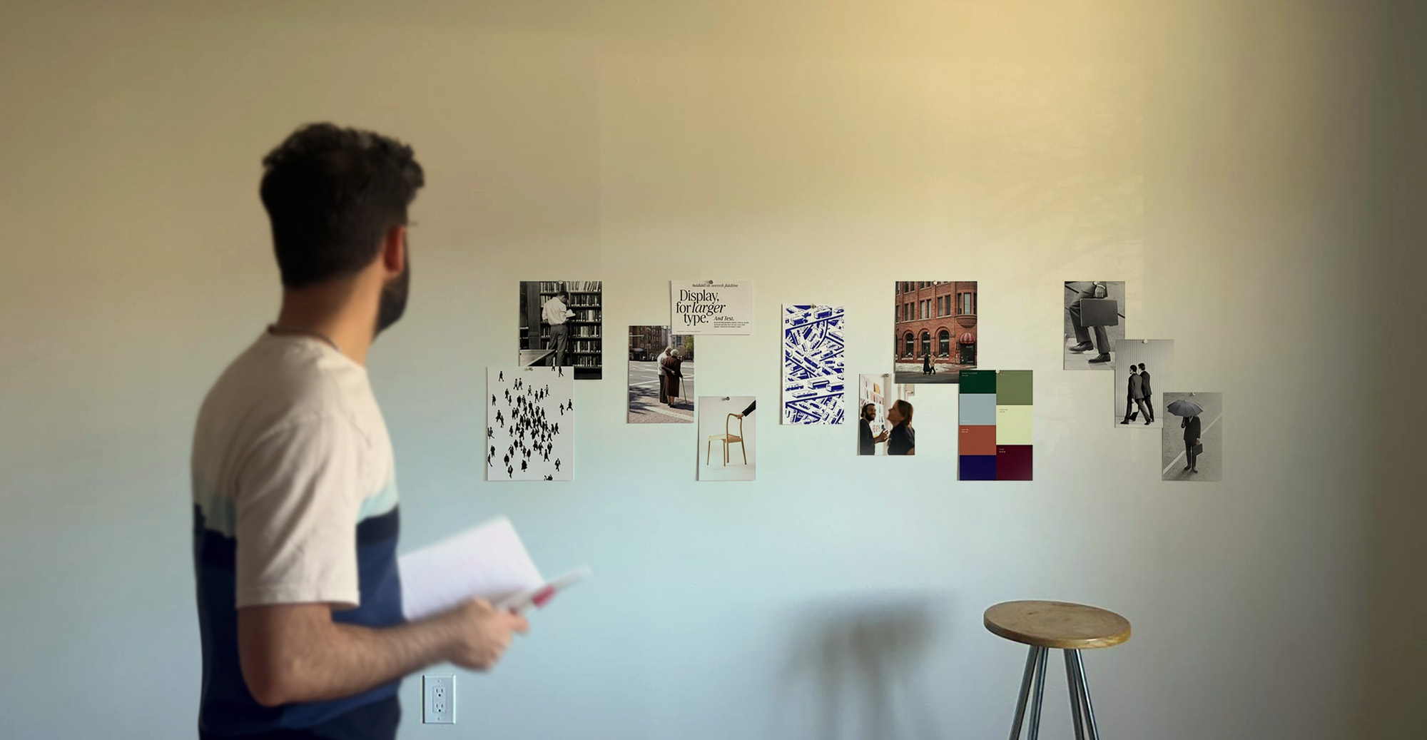 Designer reviewing mood board and visual concepts on wall for branding project.