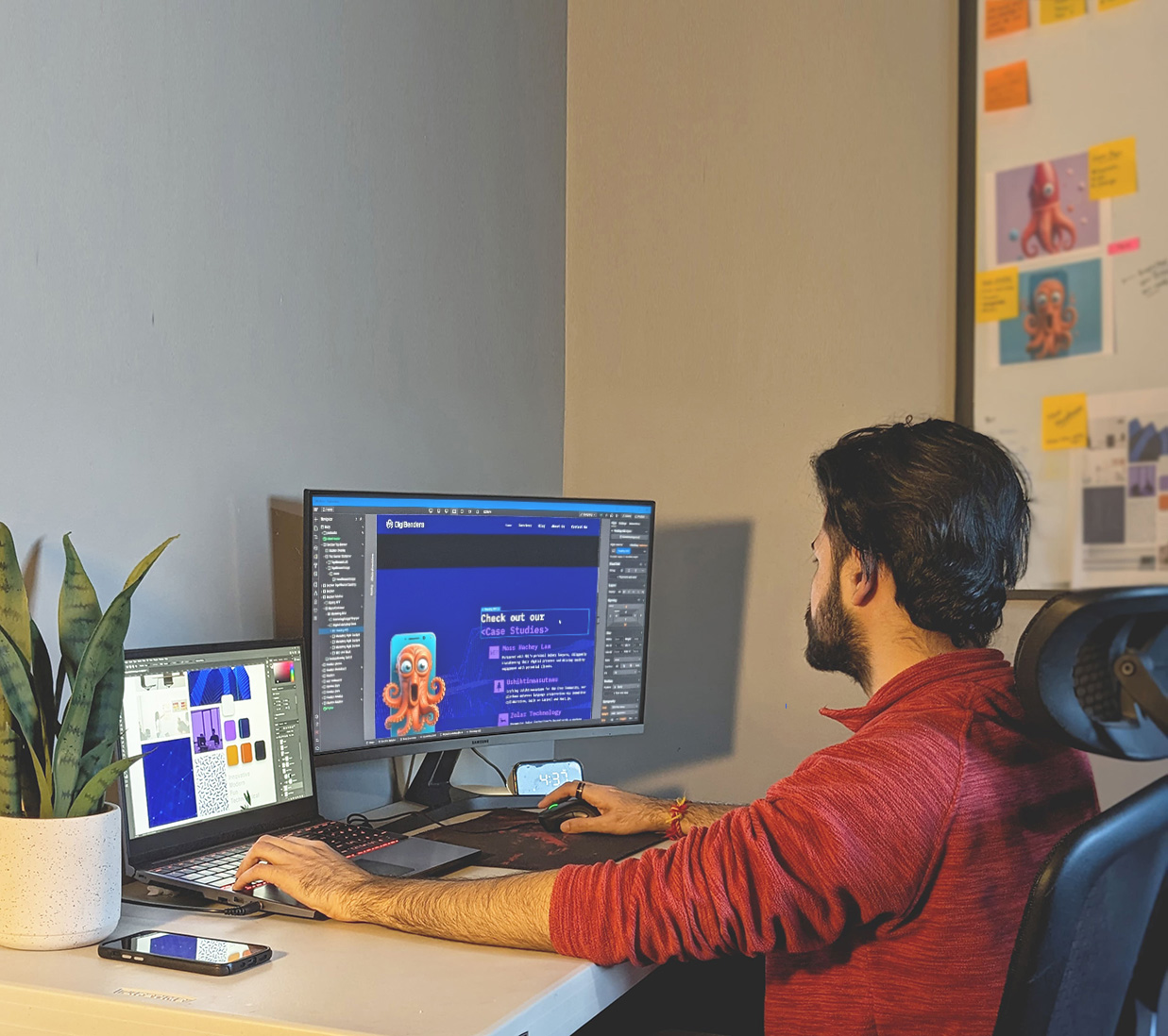 Designer working on website UI across dual screens in a modern workspace.