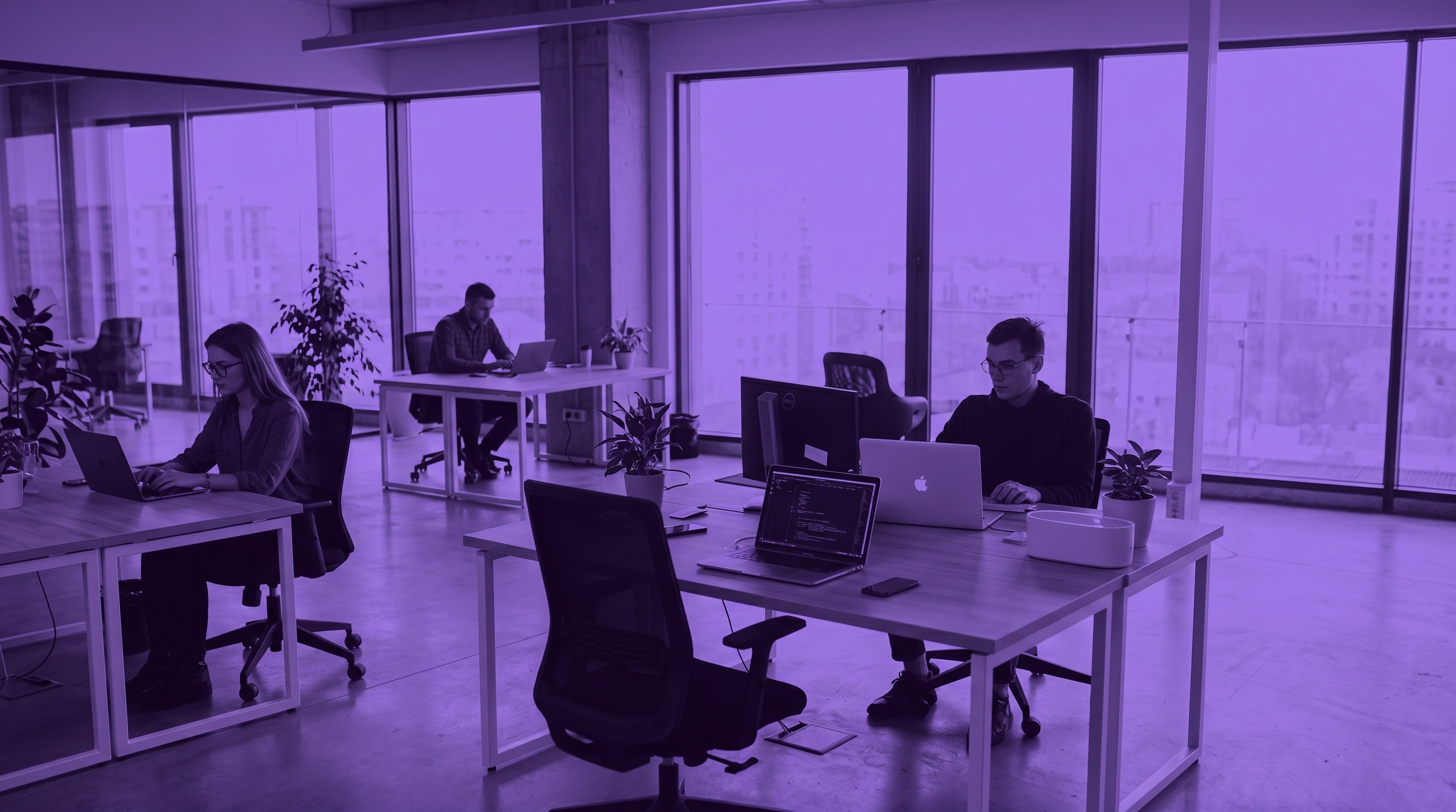 Three professionals working independently at separate desks in a modern open-plan office with floor-to-ceiling windows, overlaid with a purple tint.