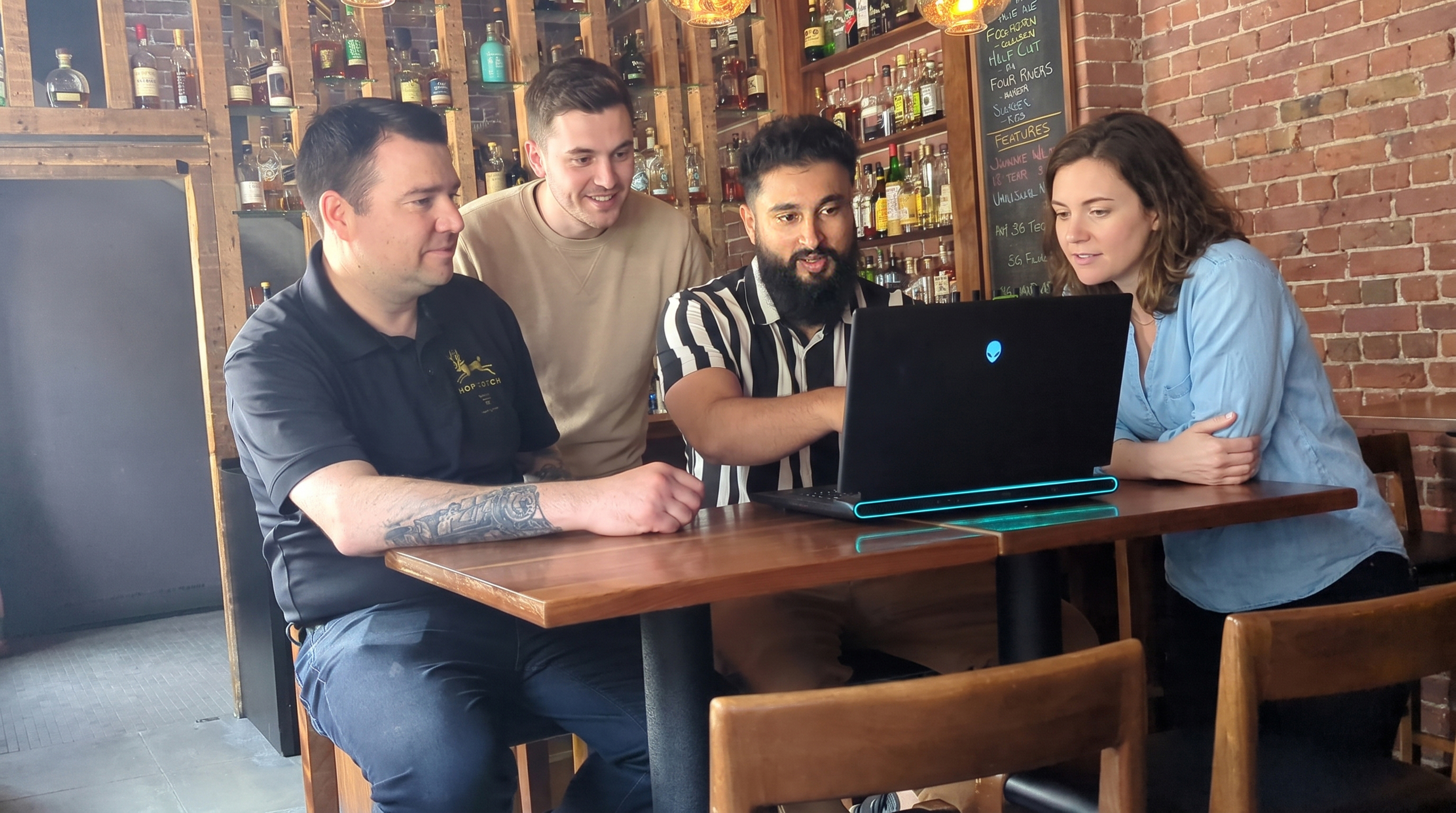 Nikhil at Hopscotch whiskey bar in Saint John, displaying website design done for them.