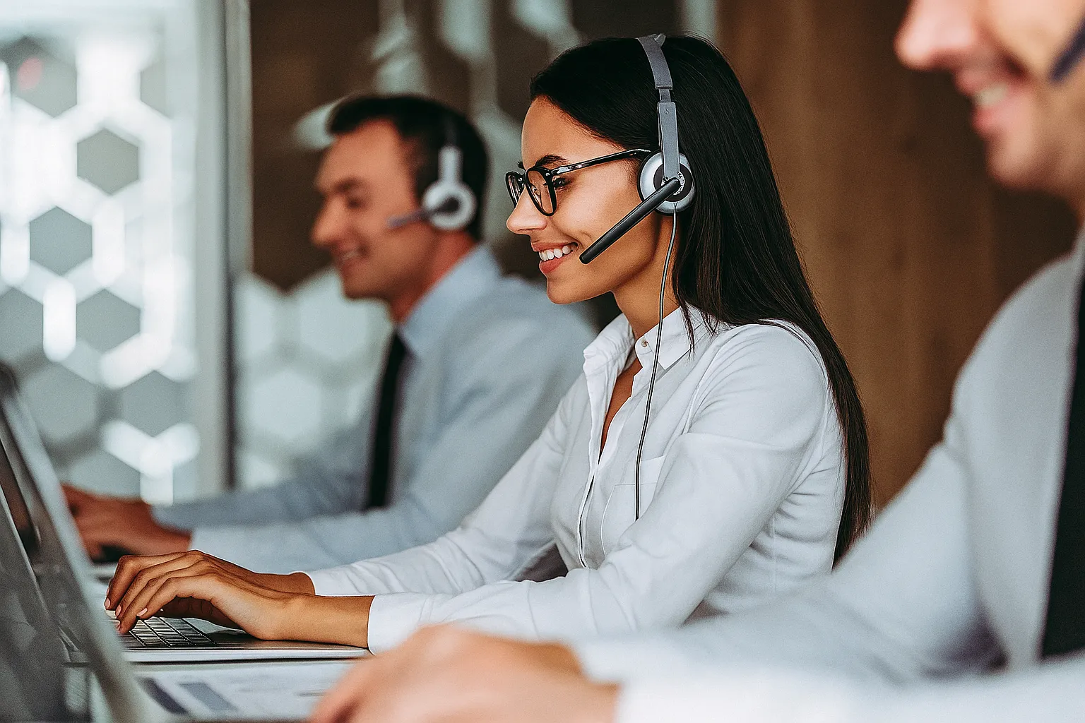 Confident support agents with headsets working on laptops