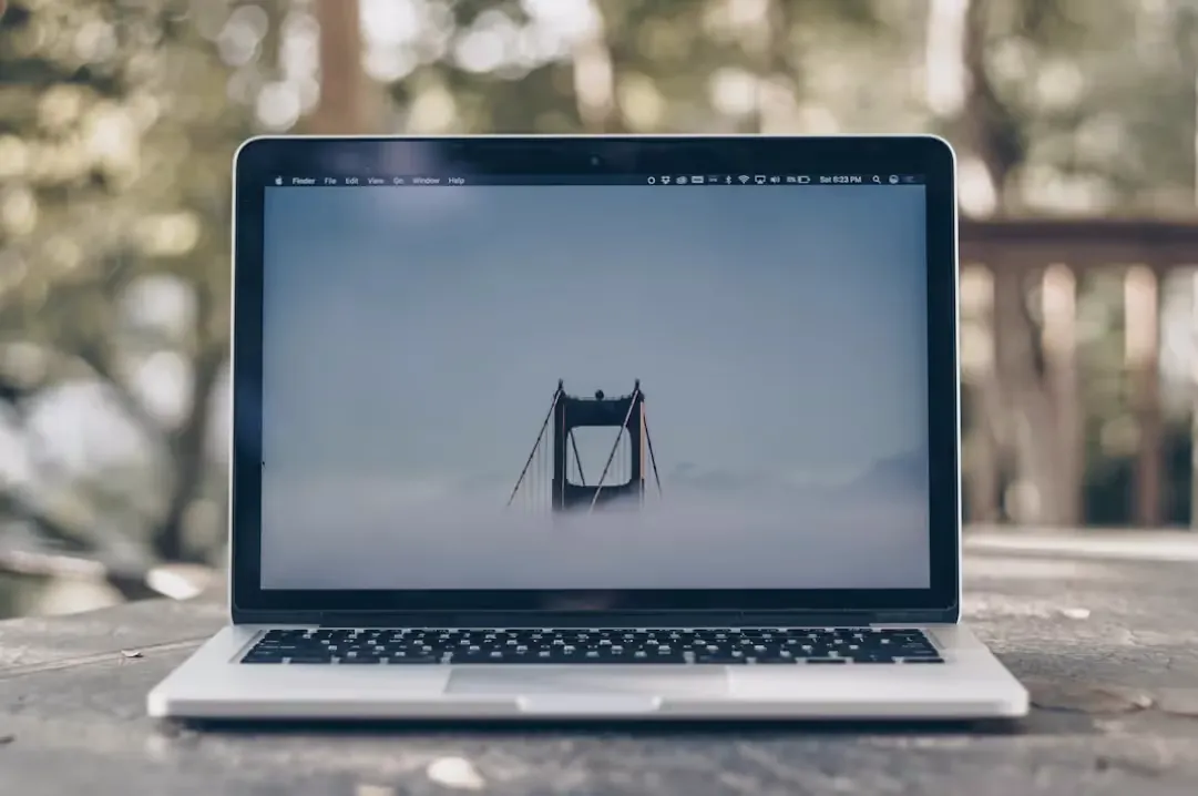 Close-up view of a laptop screen displaying an image of a bridge partially obscured by fog, with minimal desktop icons visible on the screen.