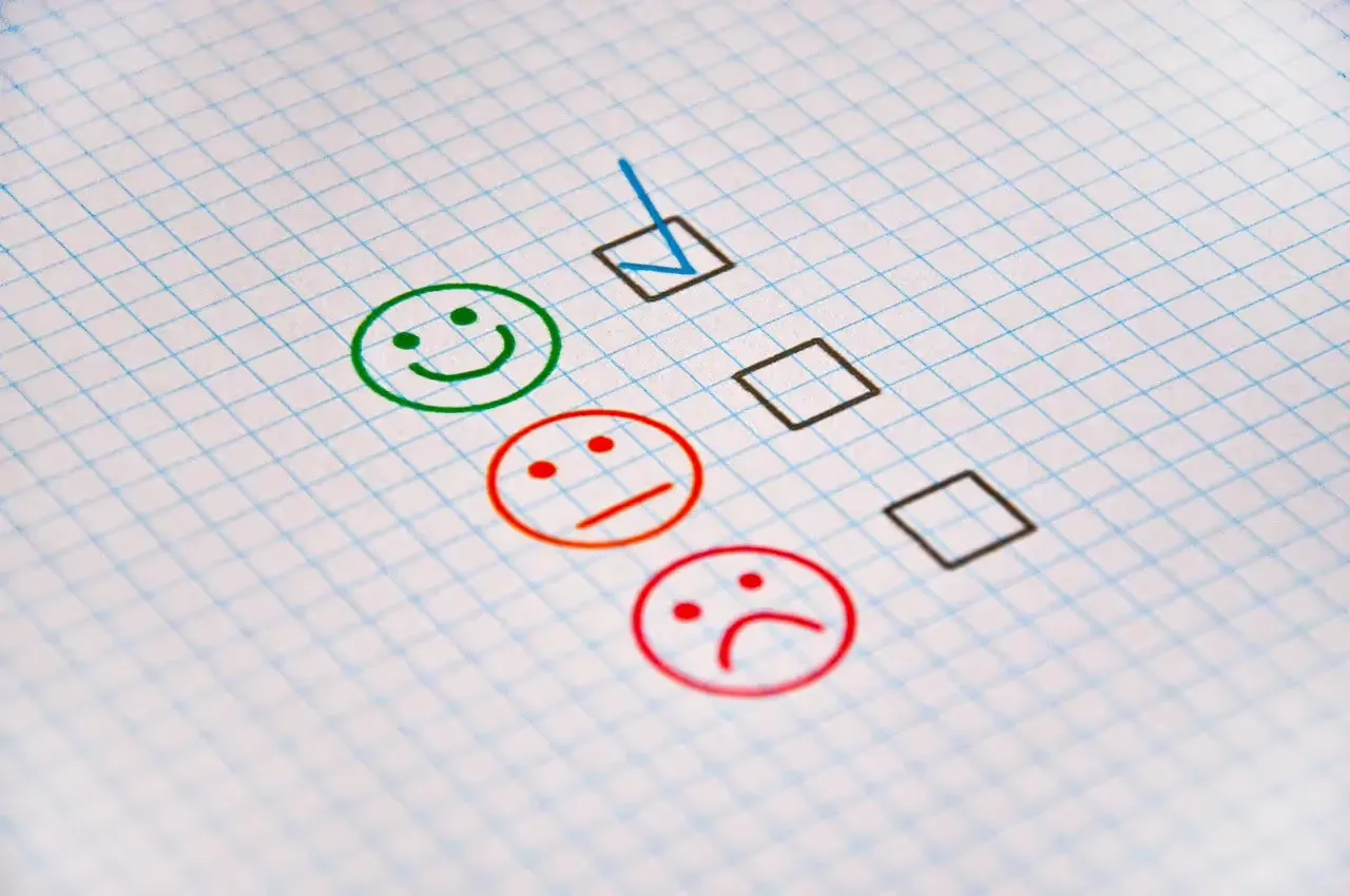 A survey form with three faces representing different levels of satisfaction: a green smiling face for positive feedback, an orange neutral face, and a red sad face for negative feedback. The checkbox next to the green smiling face is marked.