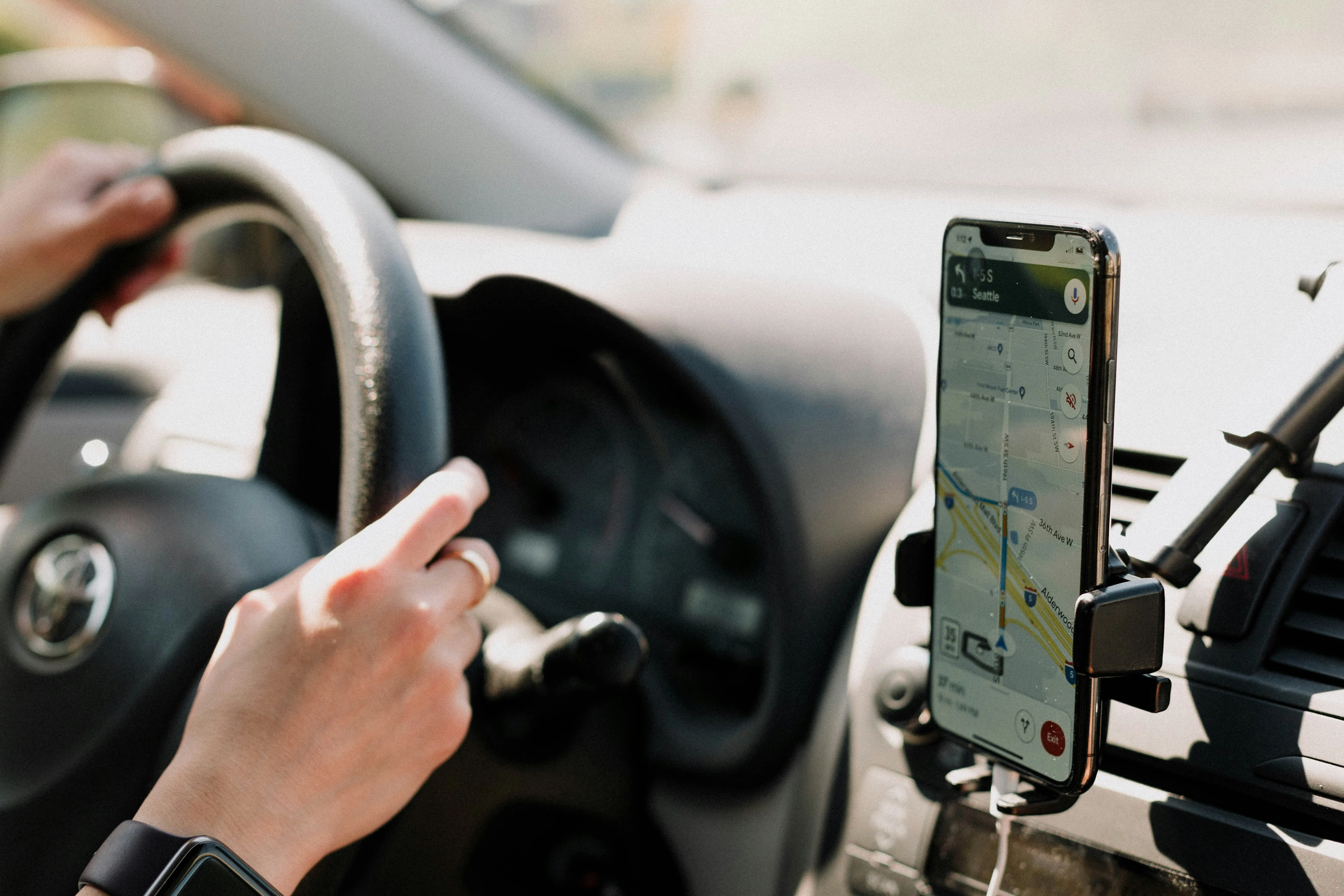 Person driving a car with Google Maps navigation open on a mounted smartphone screen, Moncton, nb.