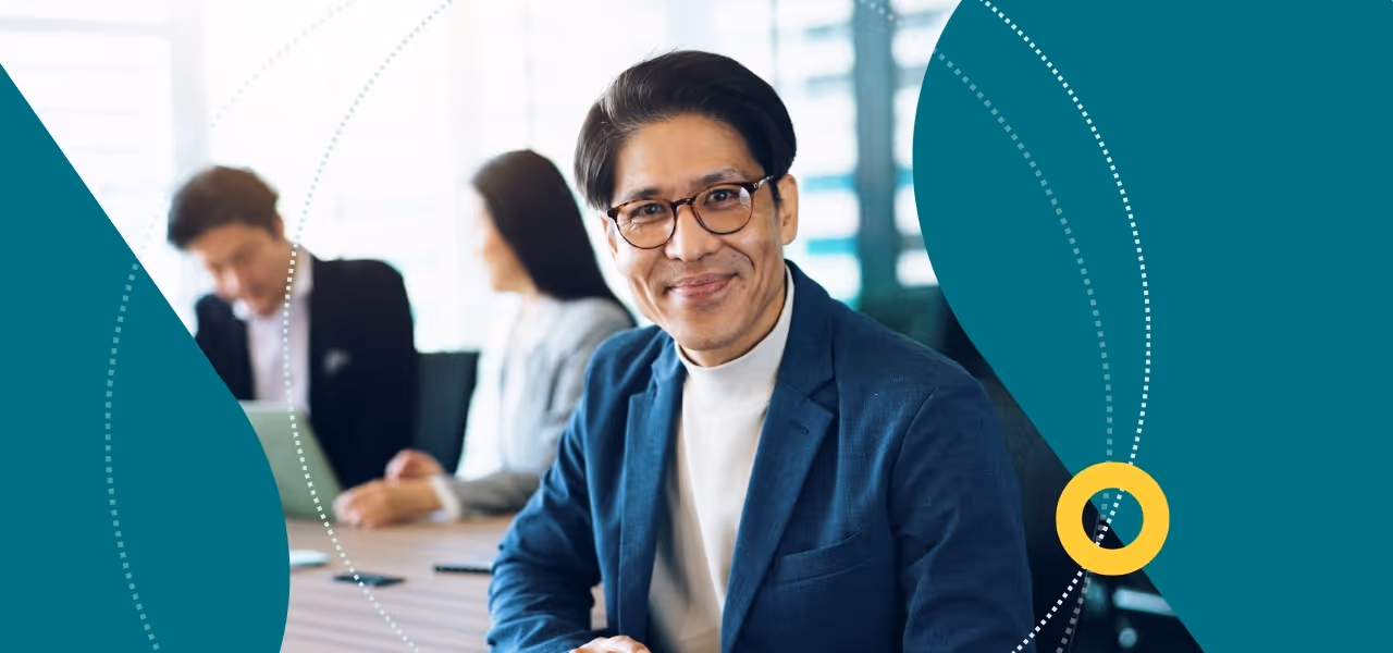 Business man in blue suit jacket seated at board table with two other directors