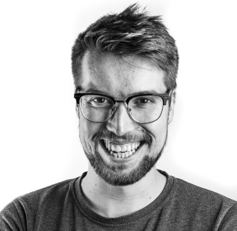 Black and white portrait of a smiling man with glasses and a beard against a white background.