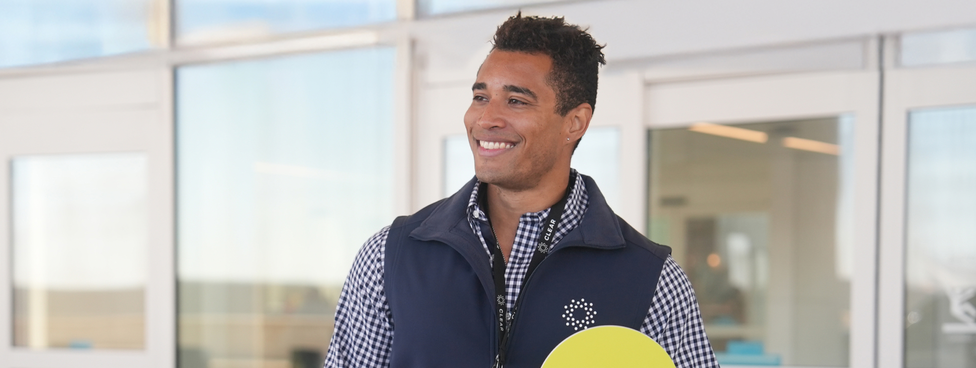 CLEAR Ambassador Holding Up a Yellow Paddle with the CLEAR Logo 