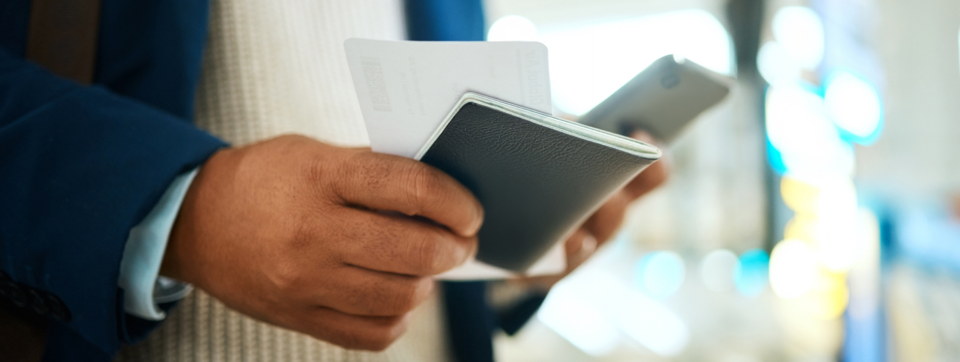 Man holding his passport, ticket, and phone in an airport