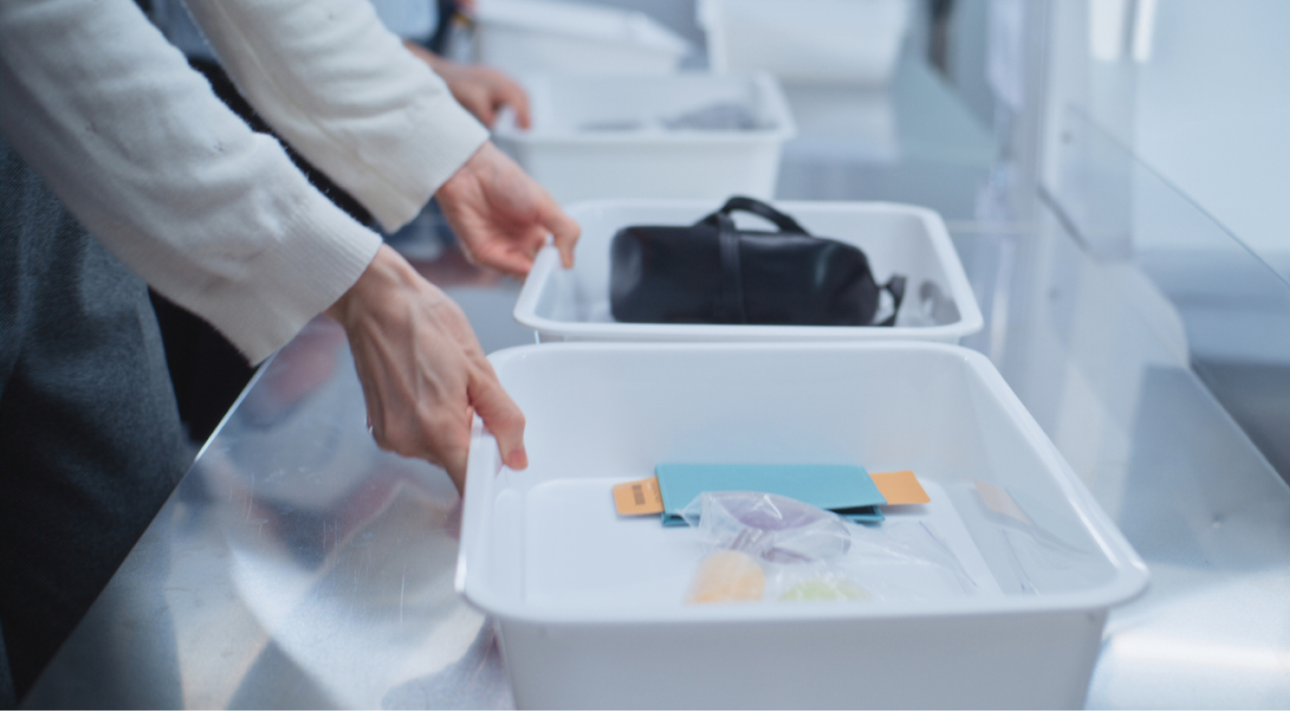 Image of person's hands on TSA bins, going through security