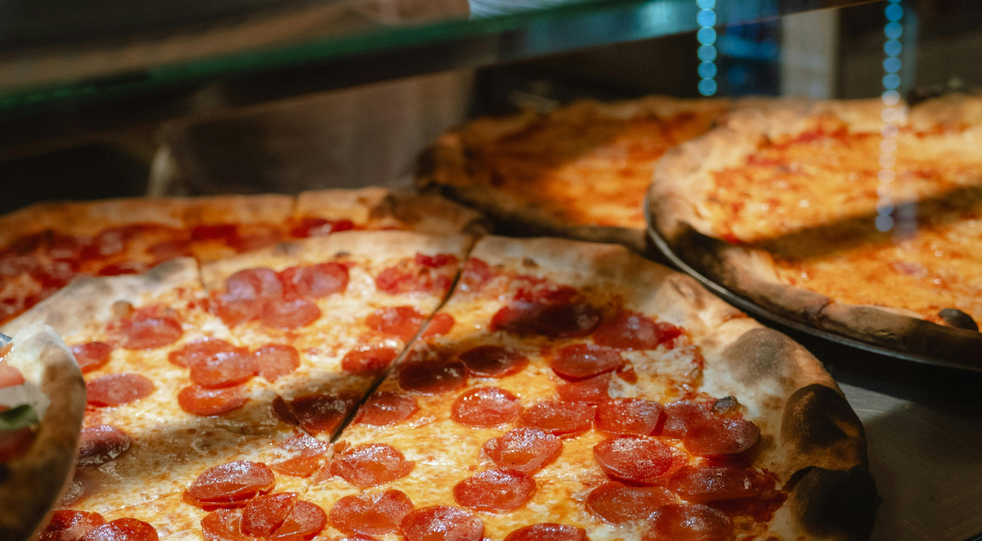 Image of pizza pies behind a glass counter