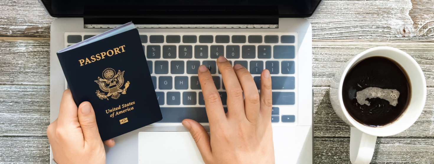 Person sitting at their laptop with a cup of coffee and their passport