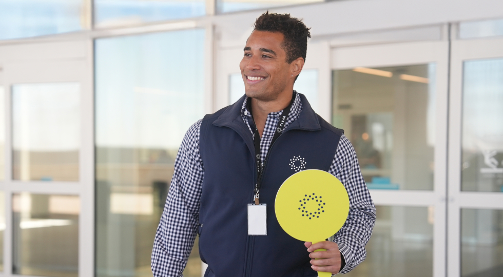 Photo of a CLEAR Ambassador holding up a CLEAR sign