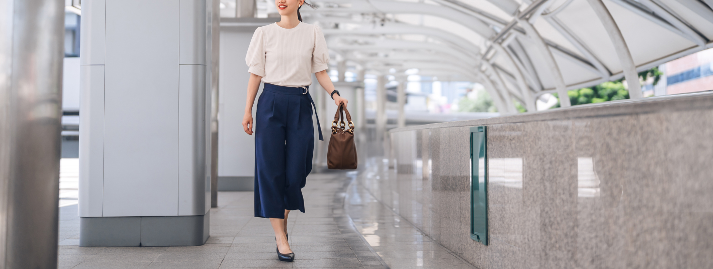Woman walking through airport holding brown purse.
