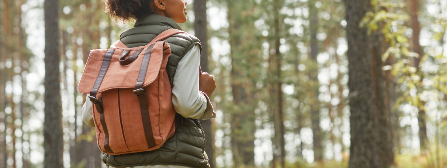 Photo of a hiker wearing a brown backpack in the woods 