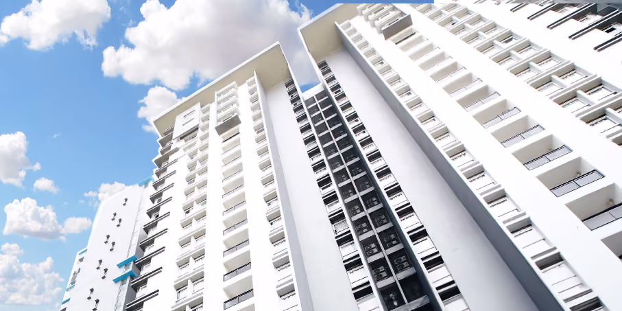Low angle view of tall white residential buildings against a blue sky with scattered clouds.