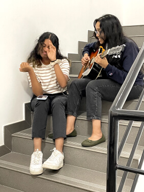 Two students in dubai singing a cover song and playing a guitar