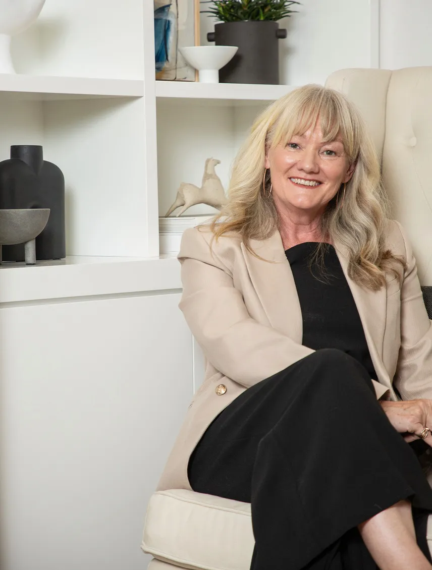 Janette sitting in study in front of decorated shelving