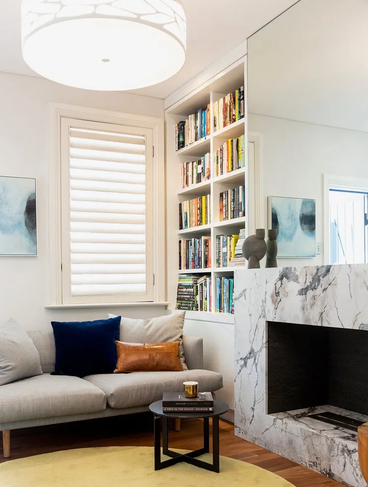Understated modern living room with fireplace and packed bookshelf