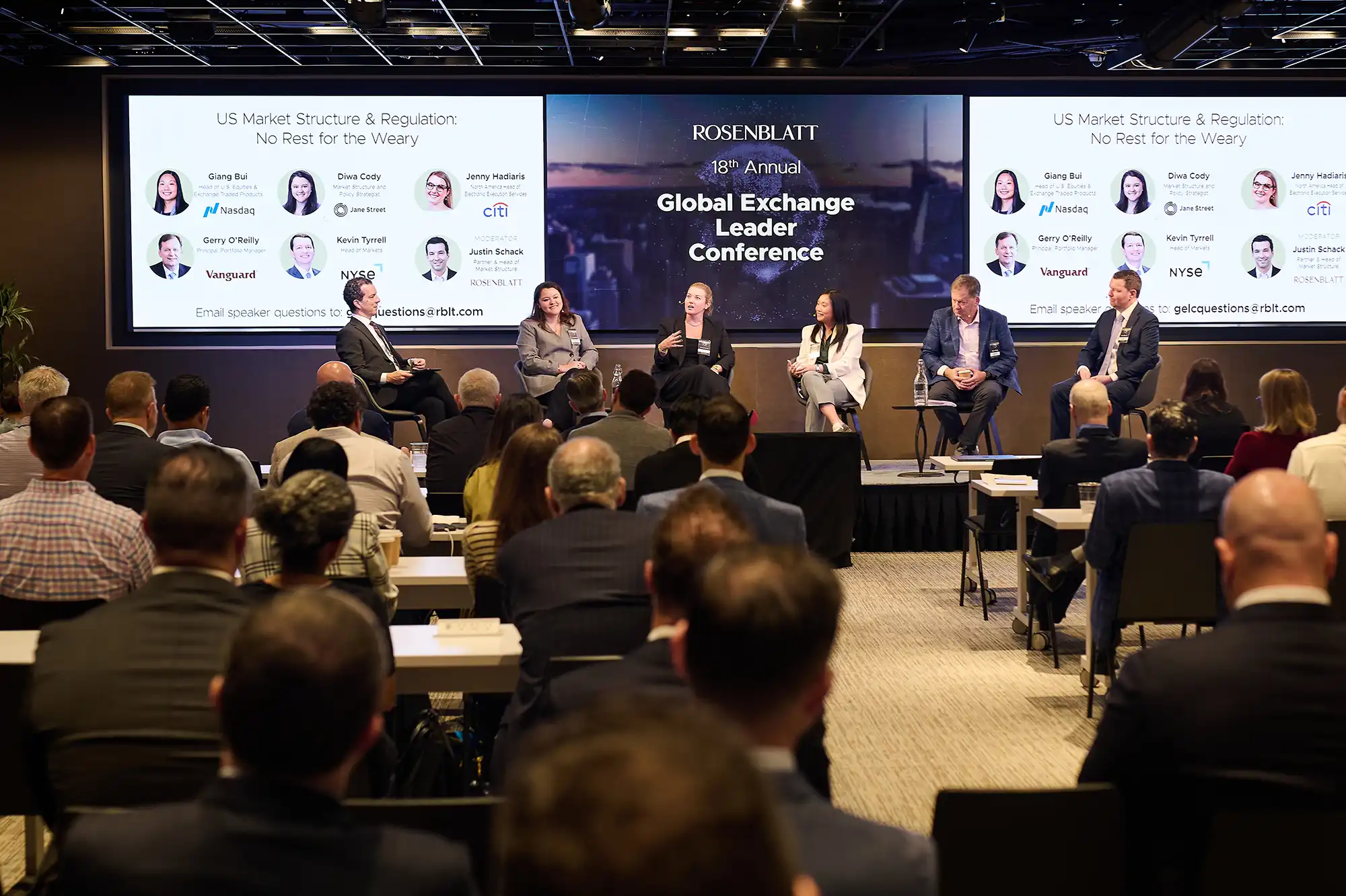 Audience members watch a six-person panel discussion on stage at the Rosenblatt Global Exchange Leader Conference in a full auditorium.