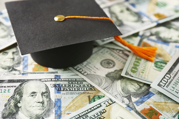 Graduation cap sitting on a pile of $100 bills