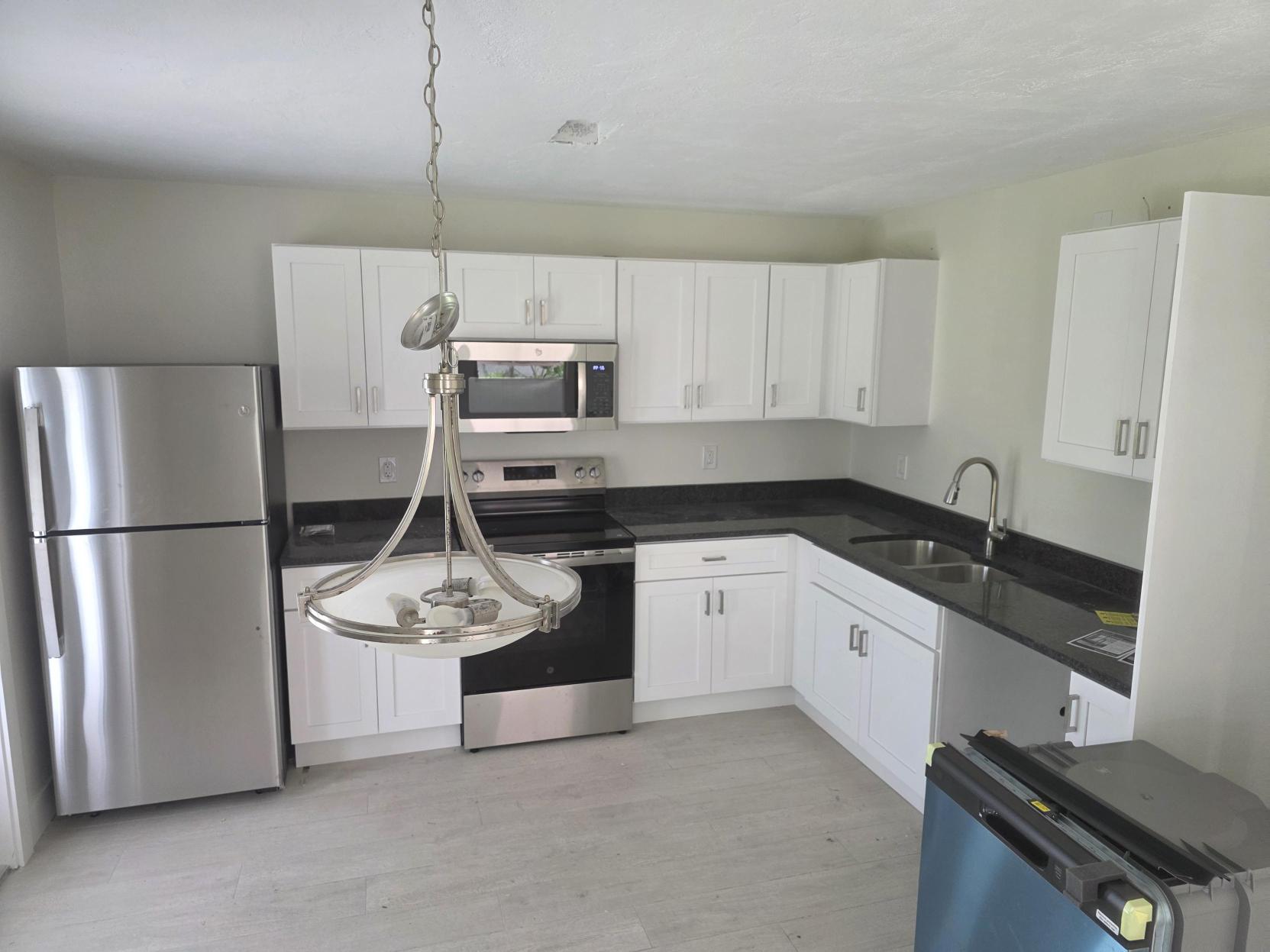 image of kitchen with white cabinets, stainless steel fridge and stove