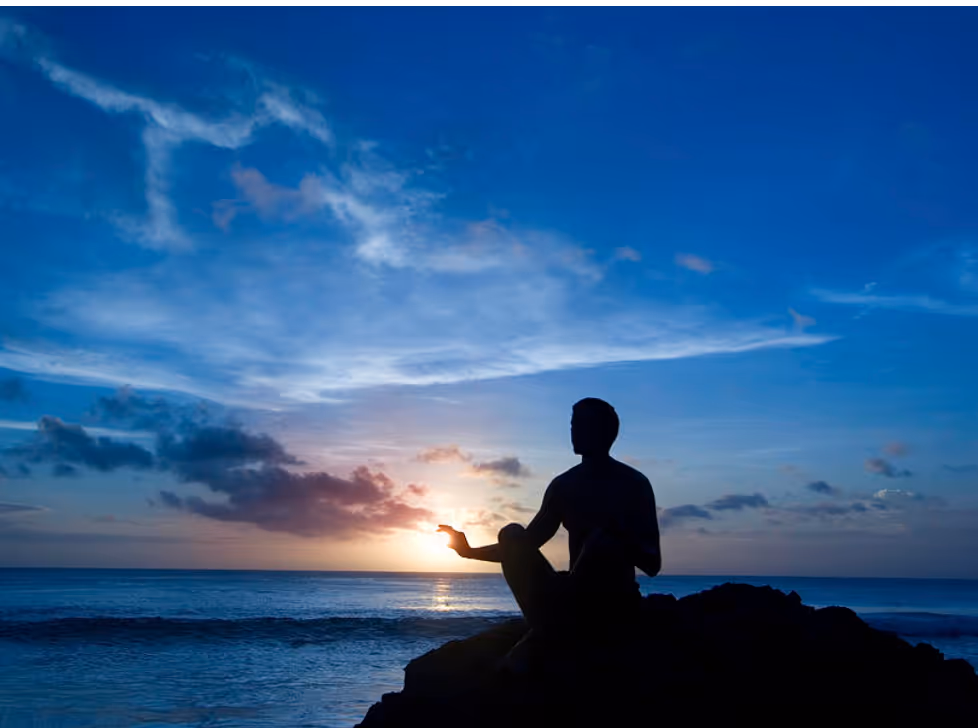 Person meditating at the edge of the water