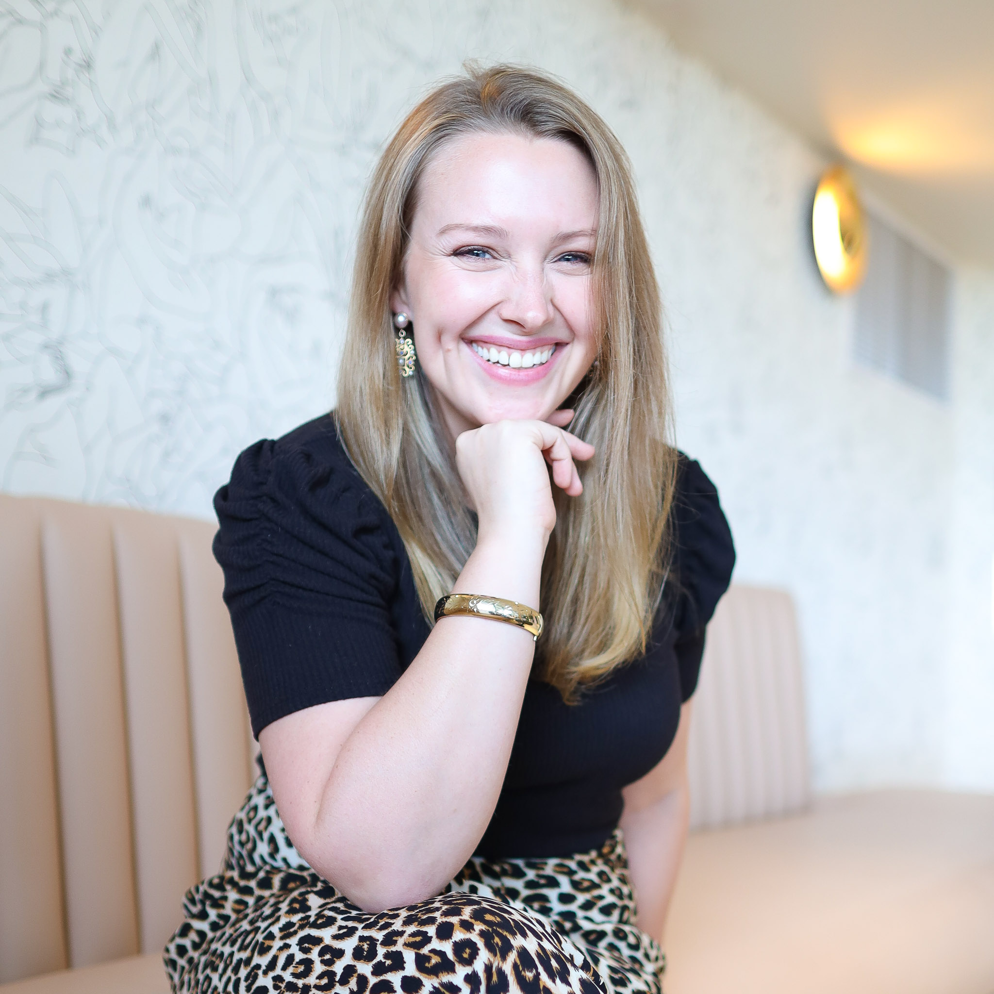 Female sitting placing hand on chin while sitting down on beige sofa smiling photography
