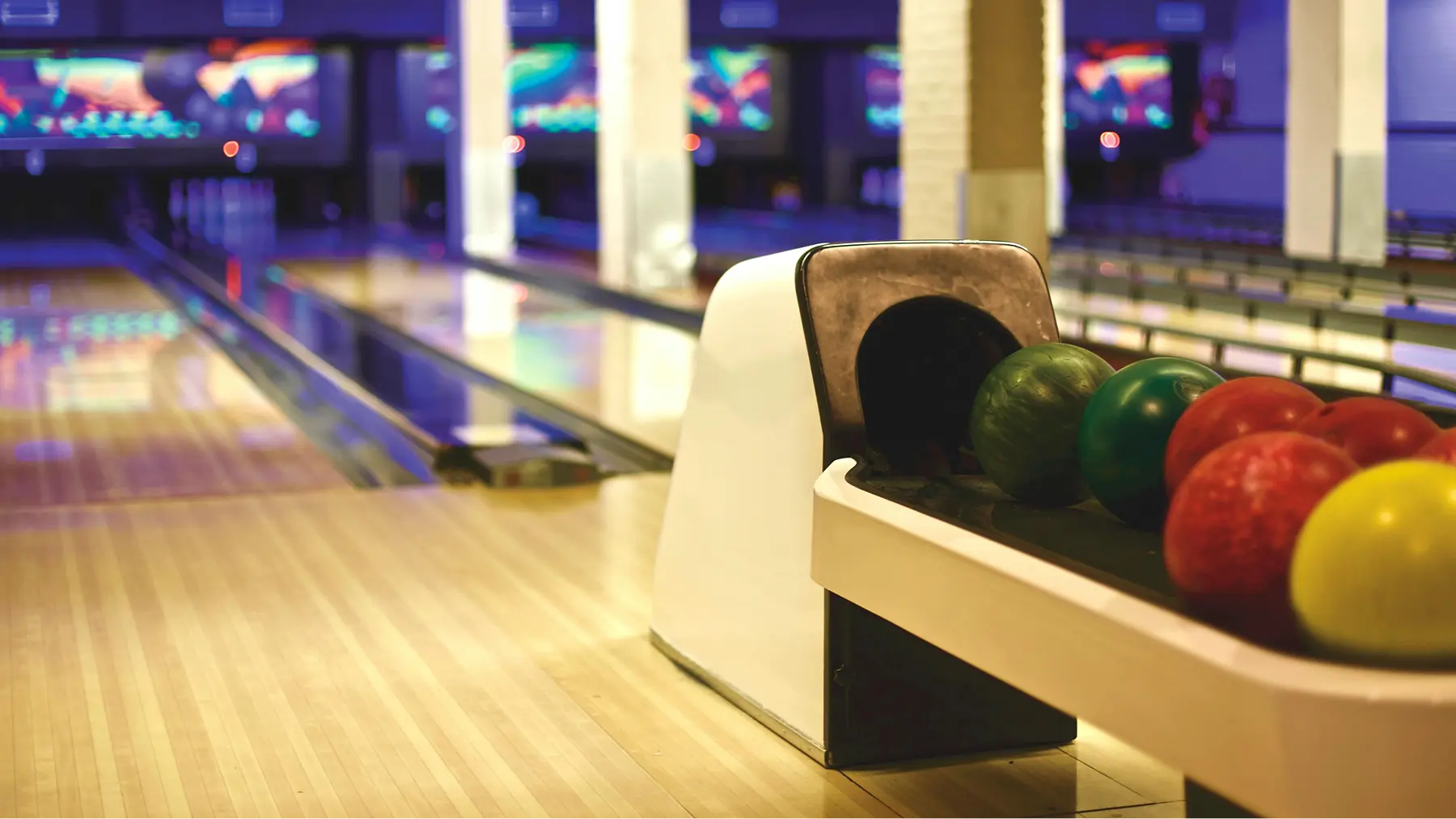 Bowl a thon setup with a close-up of colorful bowling balls on a brightly lit lane before a community fundraising event.