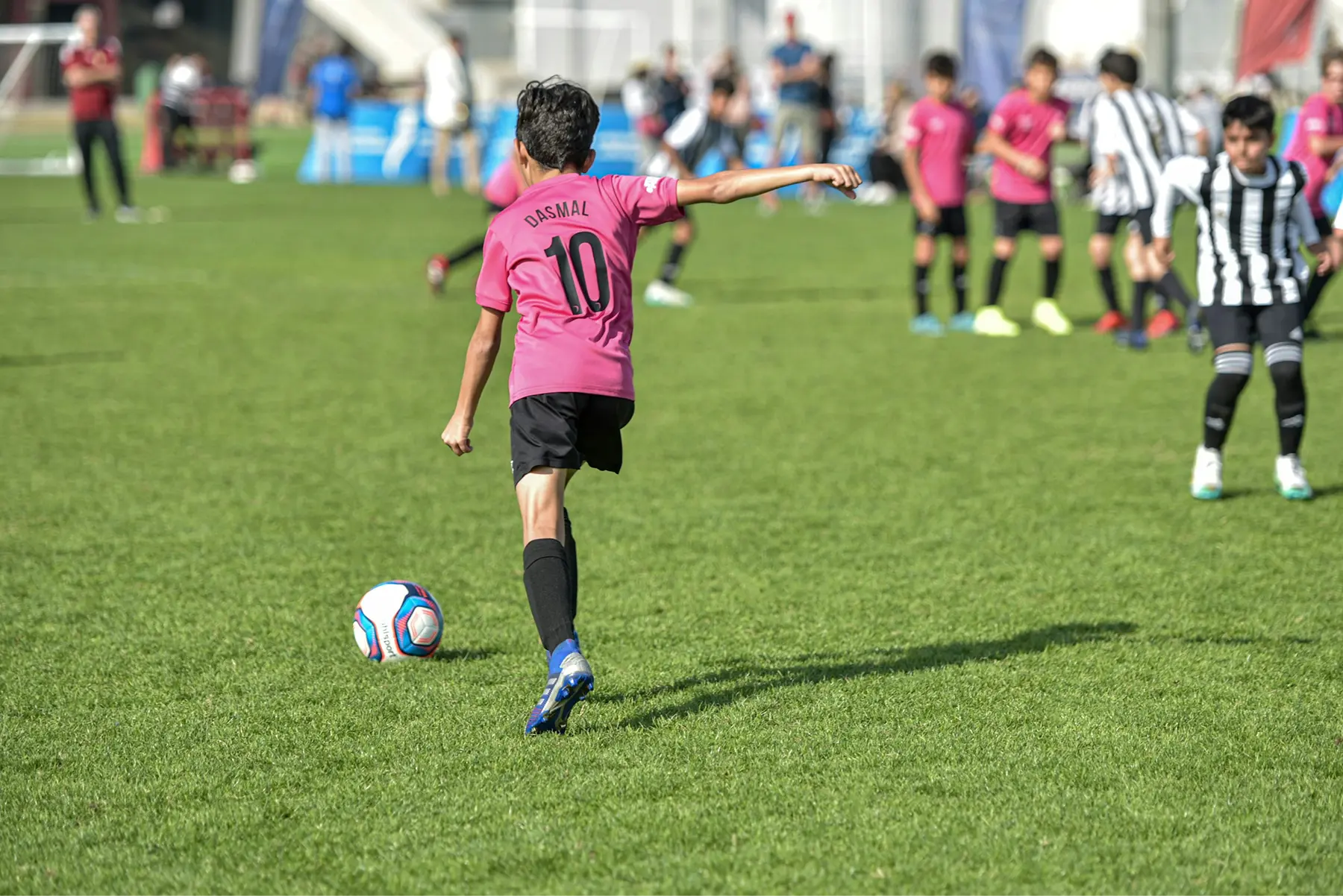 Youth soccer player kicking the ball up the field to score a goal.