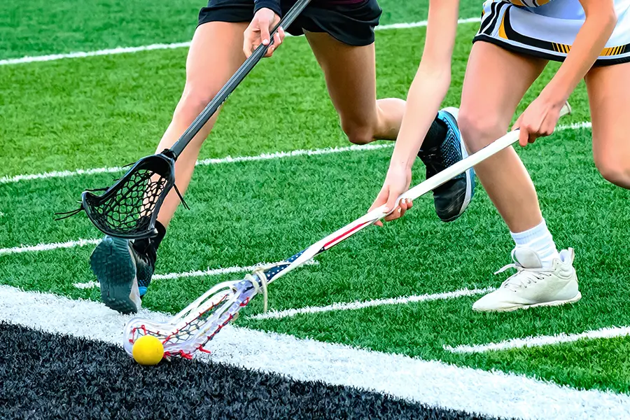 Two lacrosse players go for a groundball with sticks made possible by lacrosse fundraising.