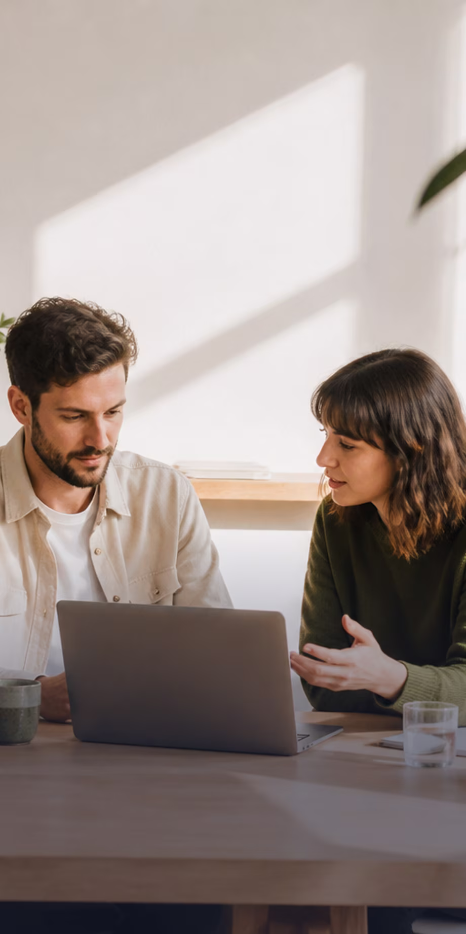 Zwei Mitarbeitende besprechen sich am Laptop im Büro