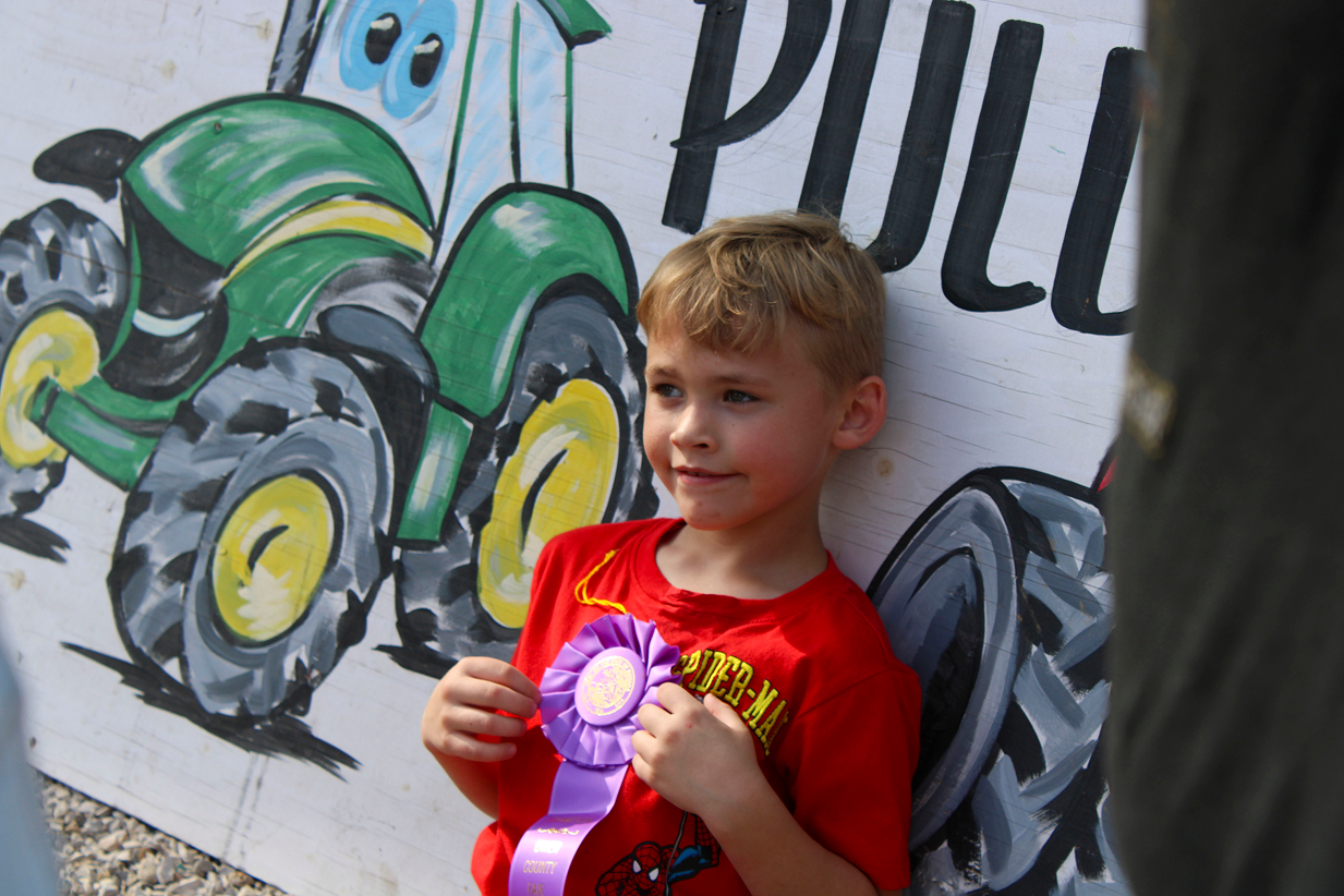 Colston Granger poses for a photo with the champion ribbon he earned during the Kiddie Tractor Pull on July 10 at the Owen County Fairgrounds. CHLOE ODEN | THE OWEN NEWS