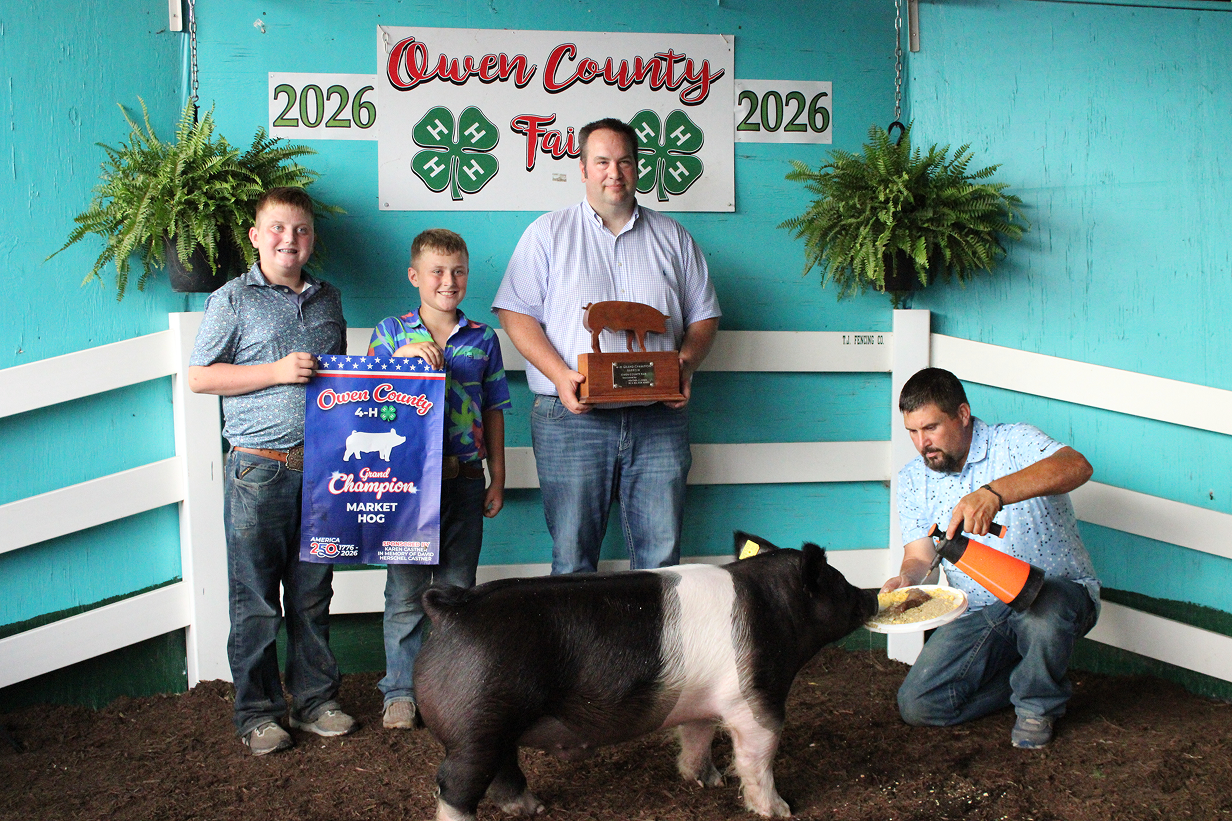 From left, Grand Champion Market Hog winner TJ Rice stands next to Hudson Rice and Judge Andon Boocher while Thurman Rice holds a plate for the pig on July 9 at the Owen County Fairgrounds. CHLOE ODEN | THE OWEN NEWS