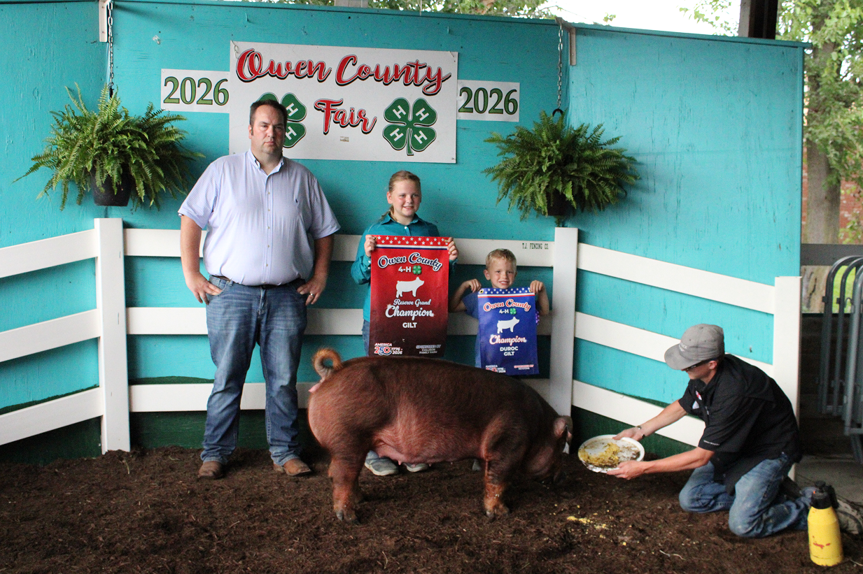 From left, Judge Andon Boocher stands next to Reserve Grand Champion Gilt winner Rowan Cooper and Wade Cooper while Keagan Shively holds a plate for the pig on July 9 at the Owen County Fairgrounds. CHLOE ODEN | THE OWEN NEWS