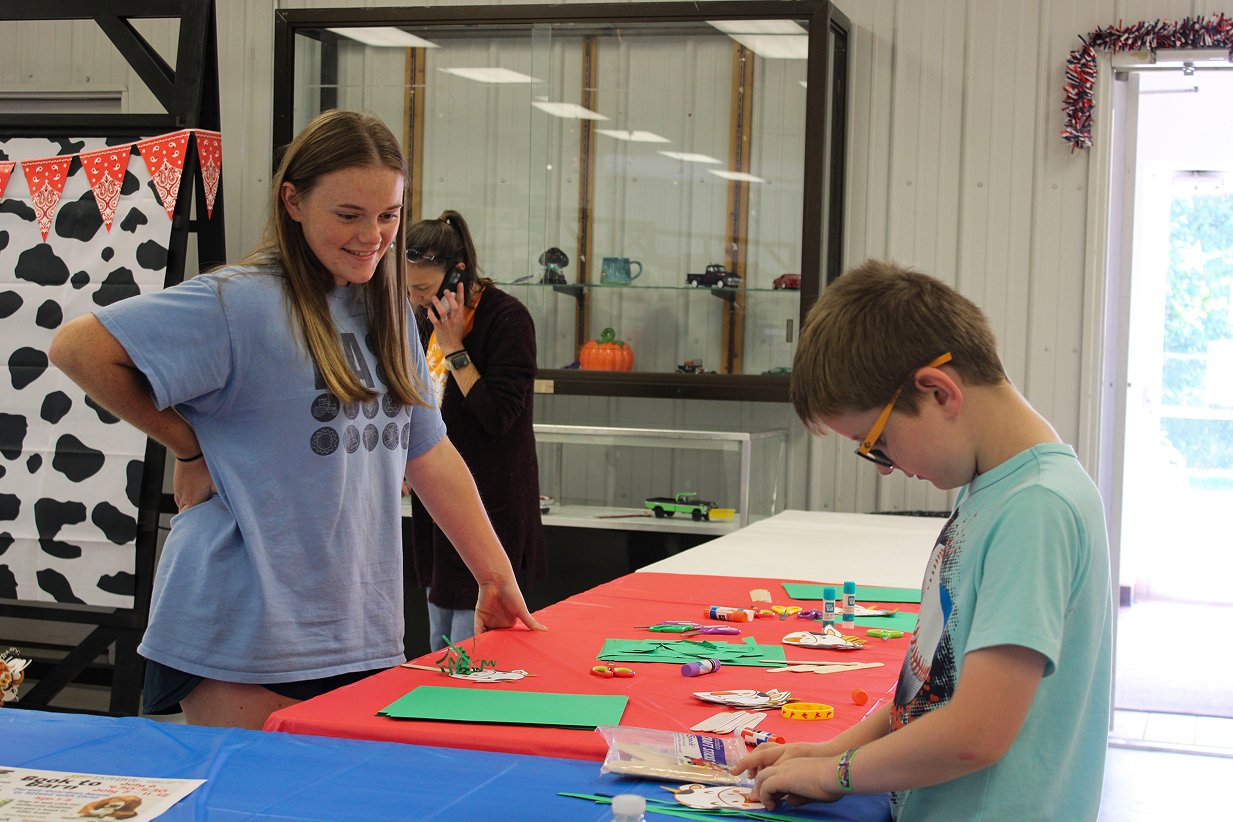 Anya DeFord watches as Winston Zigler works on a cow-themed craft at the Book 2 Barn event on July 6, 2026, at the Owen County Fairgrounds.