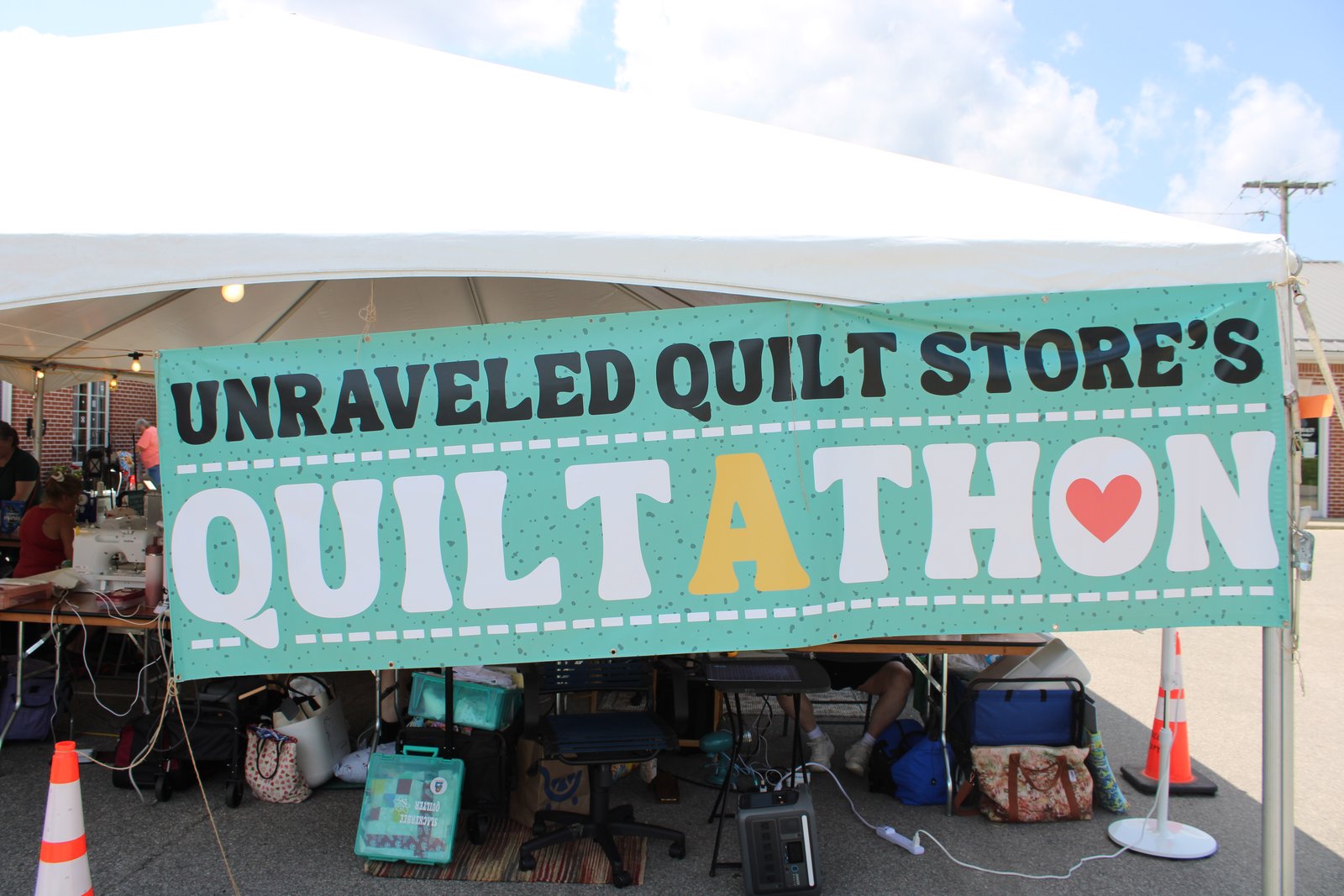 The Unraveled Quilt Store’s Quilt-a-thon banner hangs over the tent in the store parking lot. TYLER DEFORD