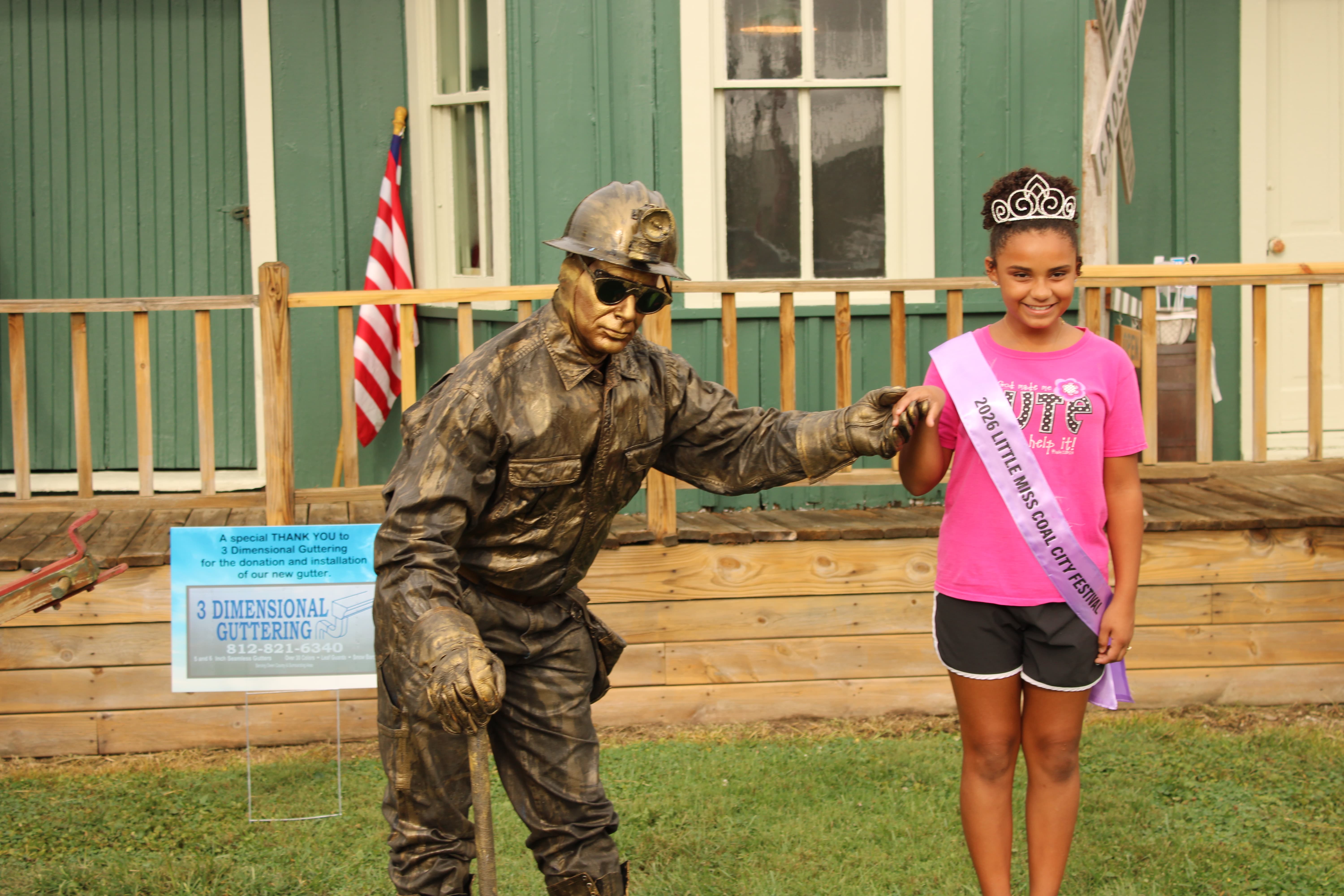 Akaiyah Rogers was crowned 2026’s Little Miss Coal City Festival. Here she poses with The Statue Guy, a feature of this year’s festival. STAFF PHOTO | THE OWEN NEWS