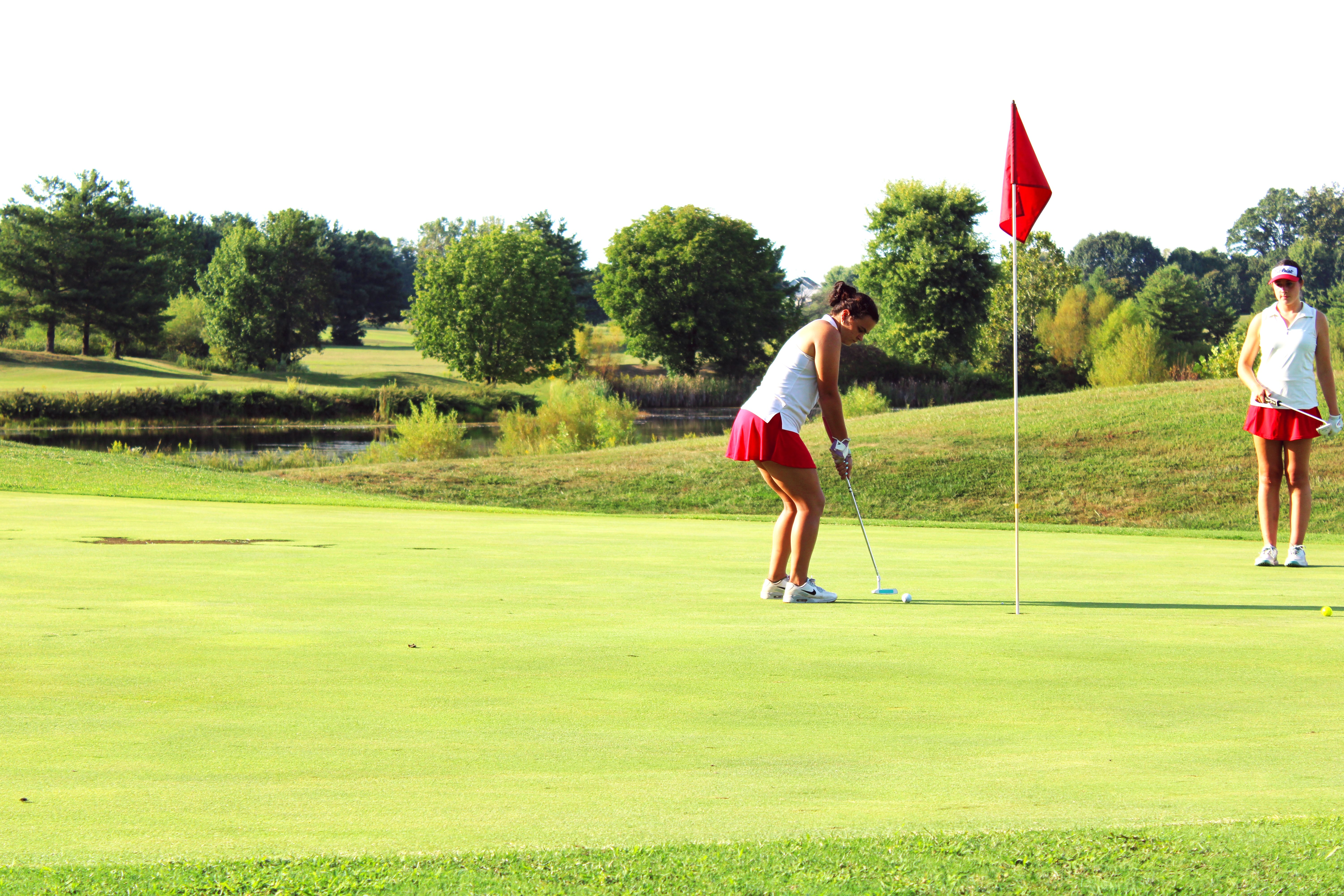 OVHS varsity golfer senior Haley Amador putts while teammate Makayla Hall looks on. STAFF PHOTO | THE OWEN NEWS