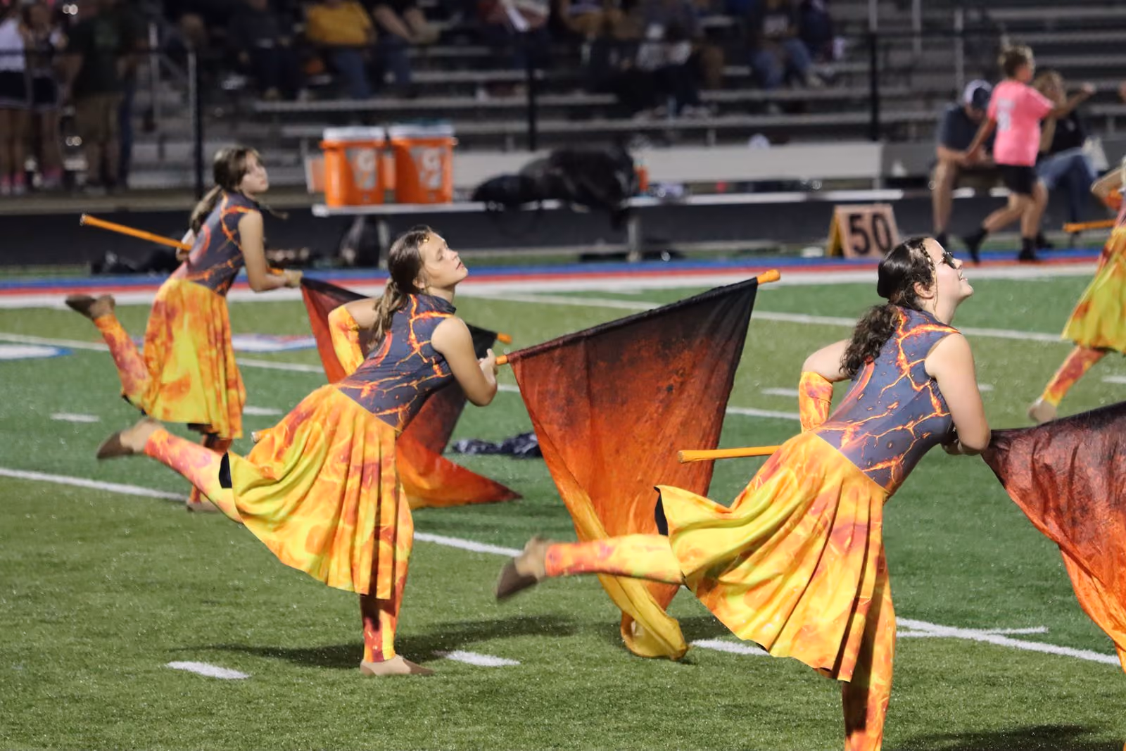 Color guard members kick and spin with flame-colored flags during the halftime show.