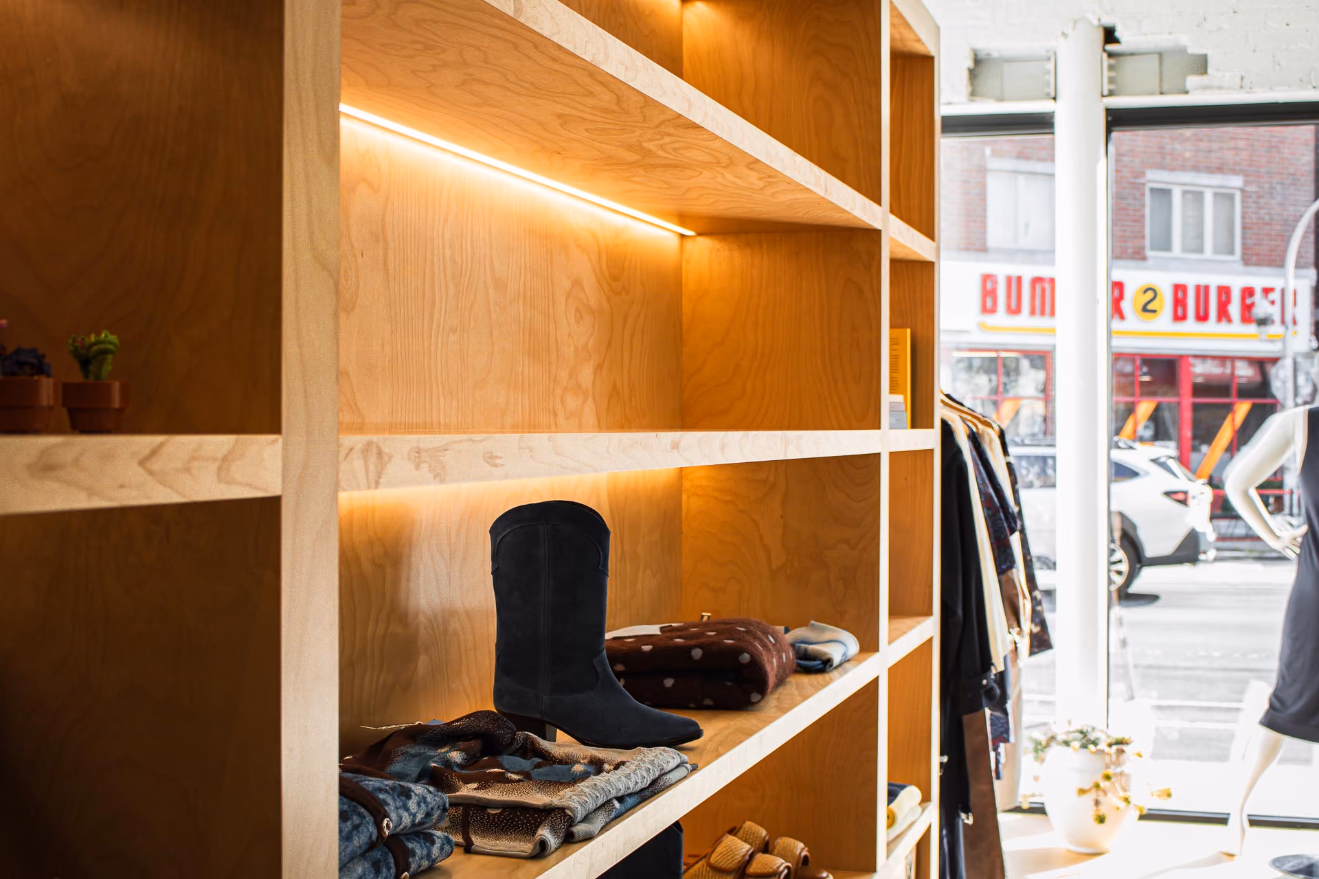 FELT Chicago lit plywood shelving with boots and knits beside the street-facing window