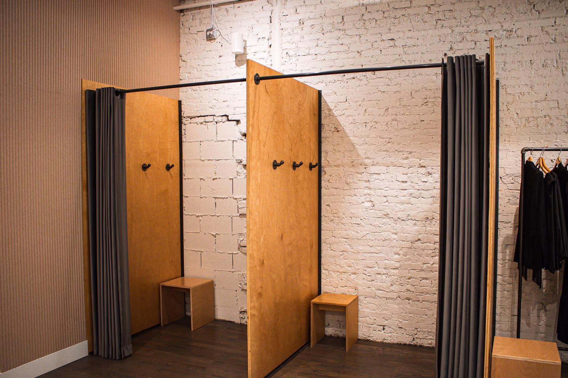 FELT Chicago fitting rooms with plywood partitions, curtains and white brick walls