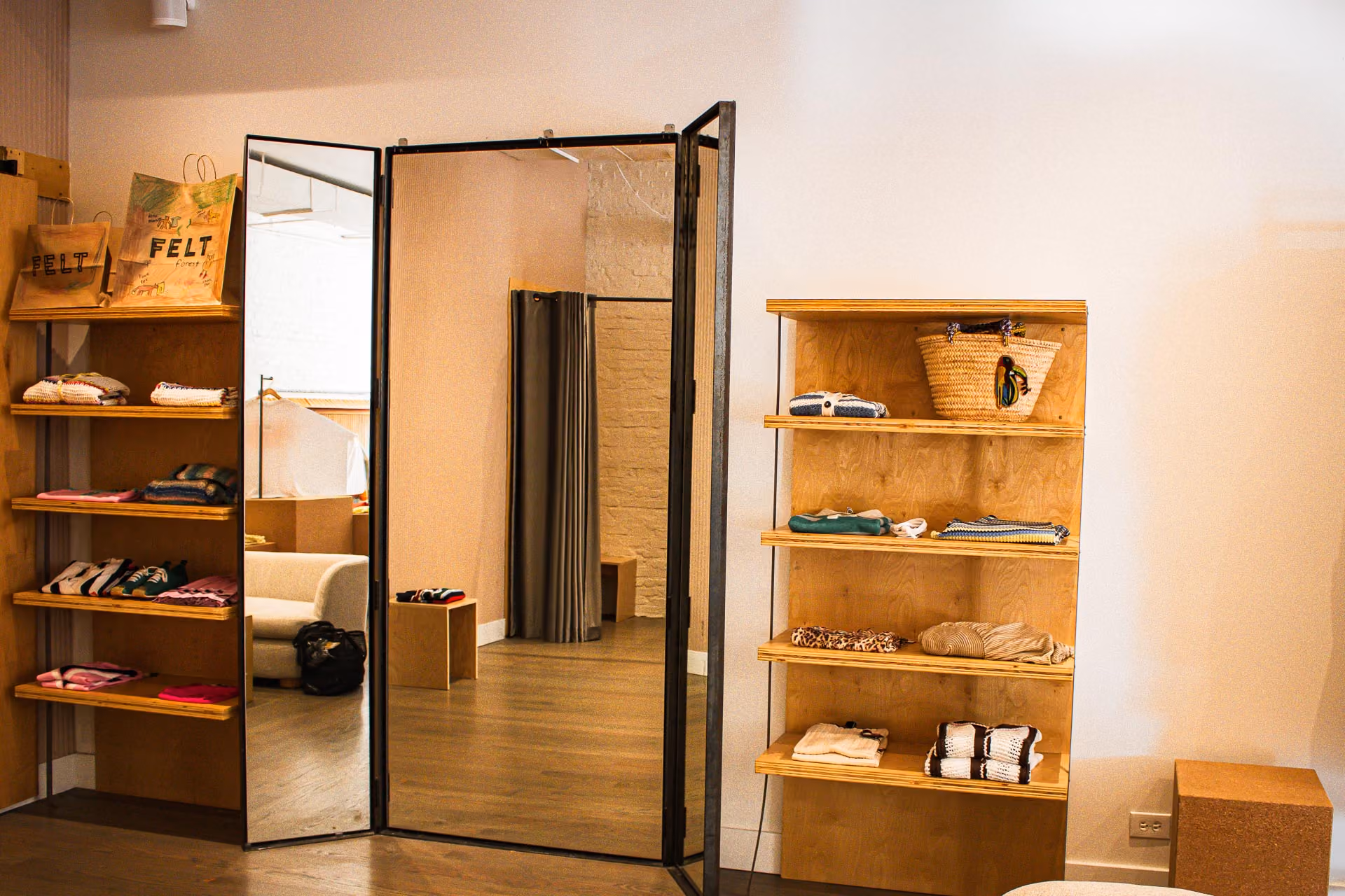 FELT Chicago fitting room entry with a folding mirror flanked by plywood shelving