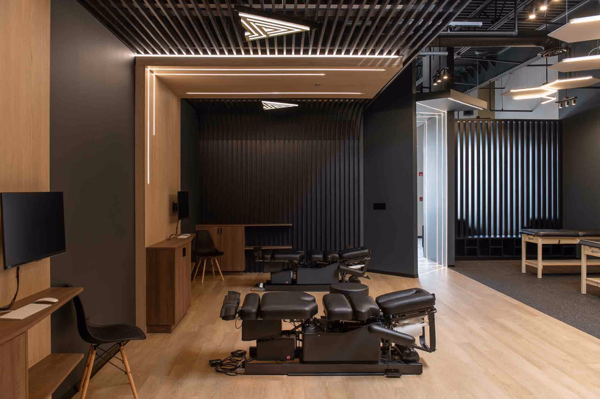 Adjusted Health + Performance treatment bay with adjusting table under a wood-slat ceiling and LED lines