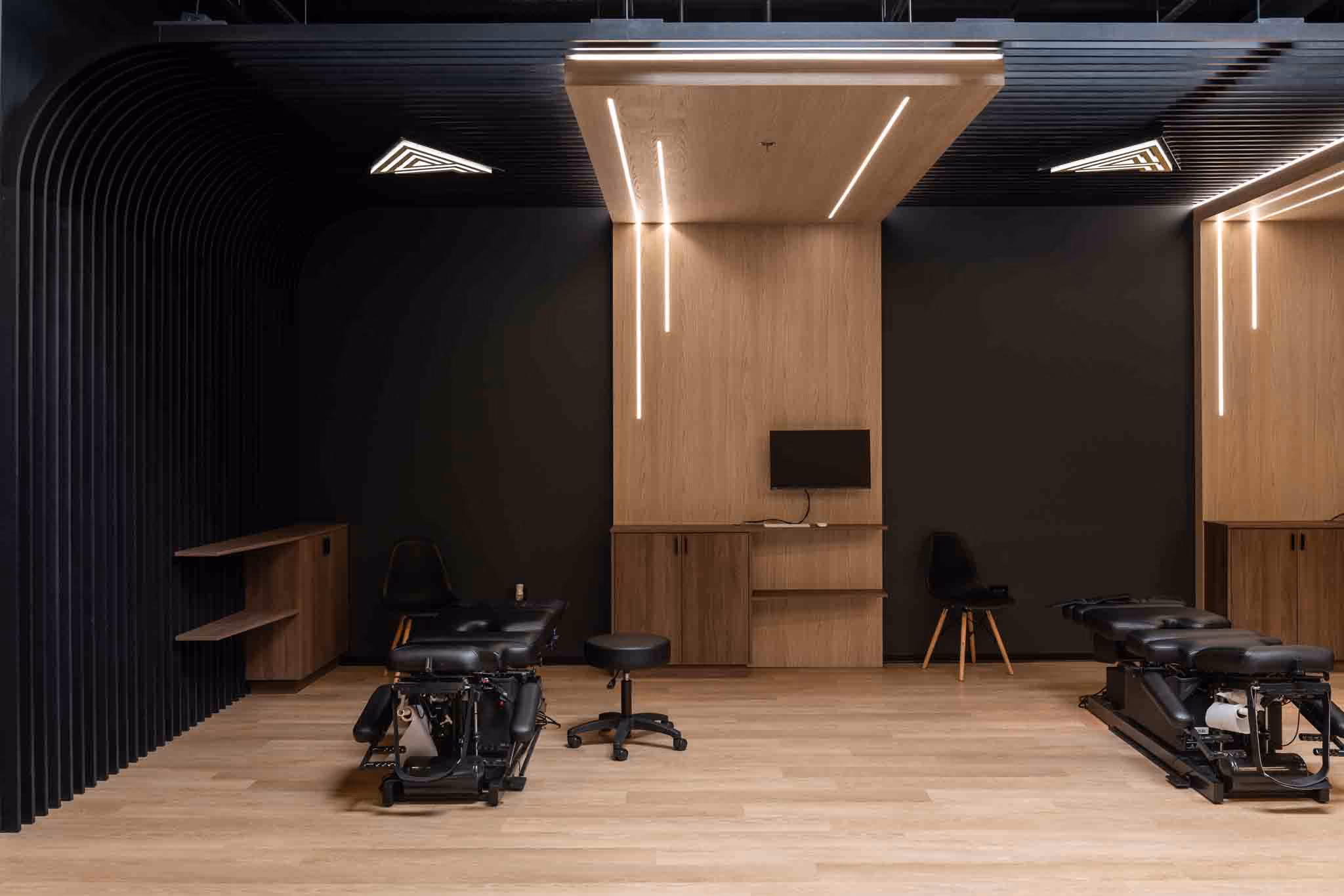 Adjusted Health + Performance open treatment area with adjusting tables beneath a suspended wood canopy
