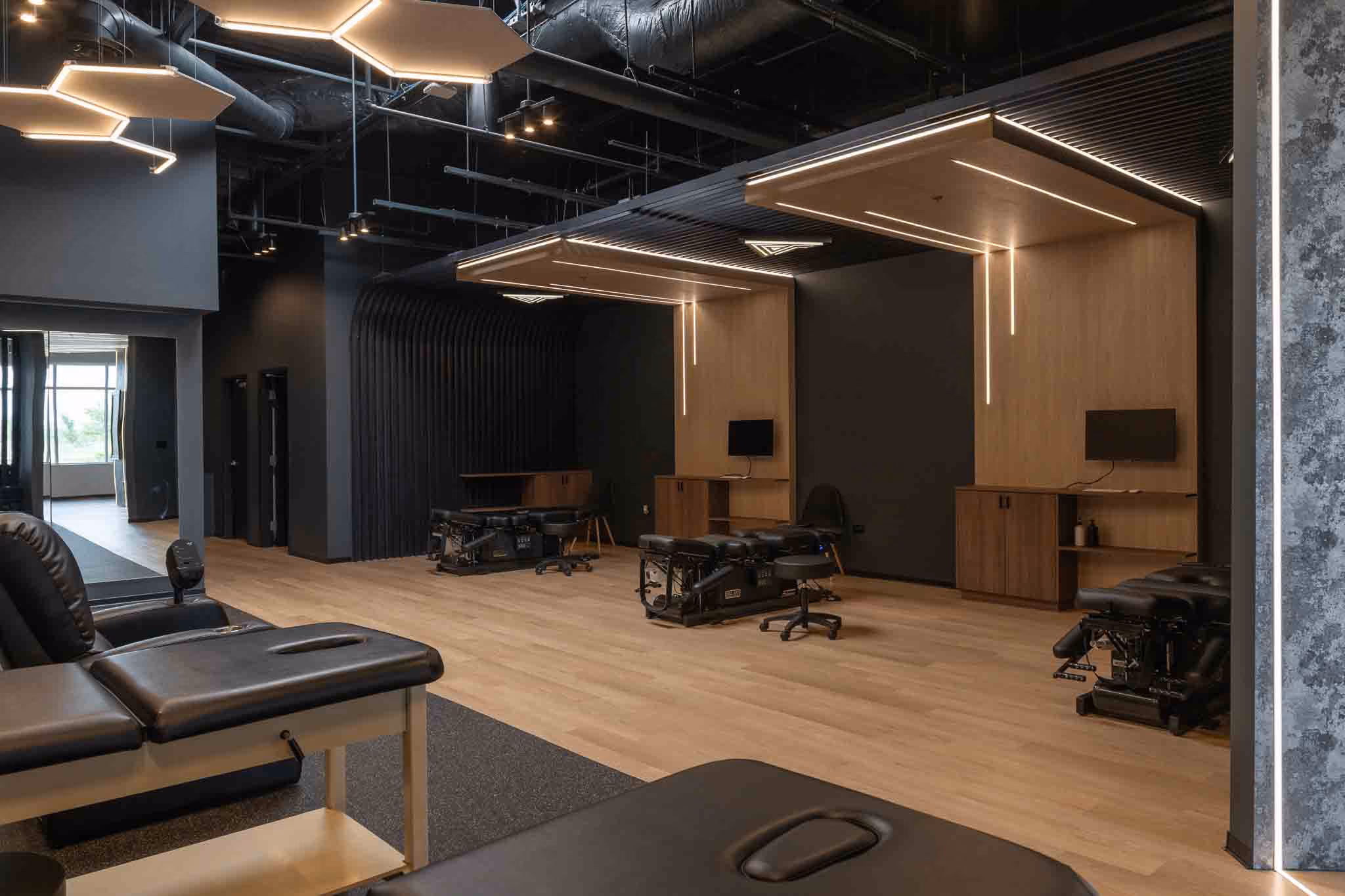 Adjusted Health + Performance clinic floor with hexagon lighting, wood canopies and treatment tables