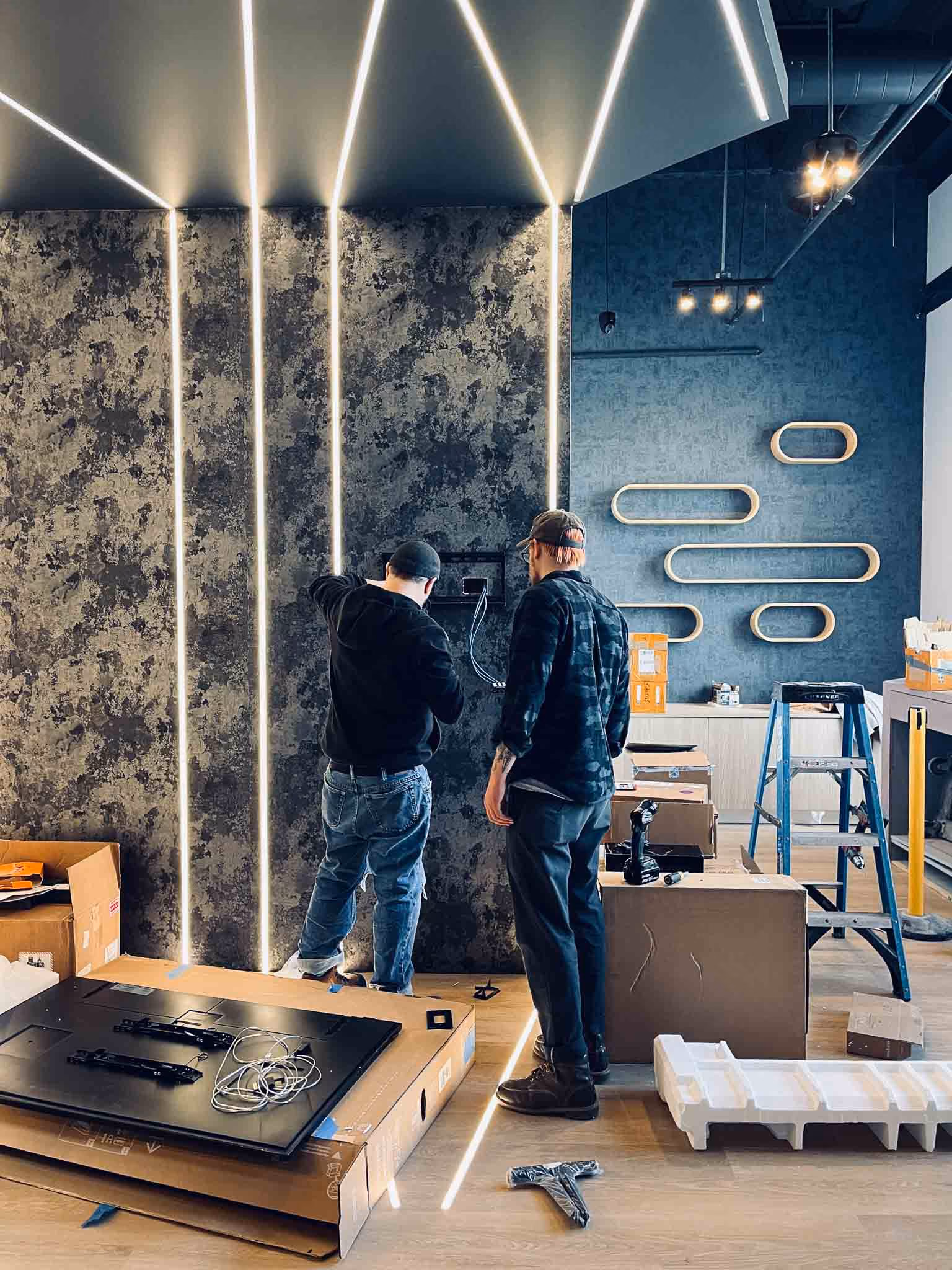 Klasik Construction crew installing oval wall shelves and LED lighting at Adjusted Health + Performance