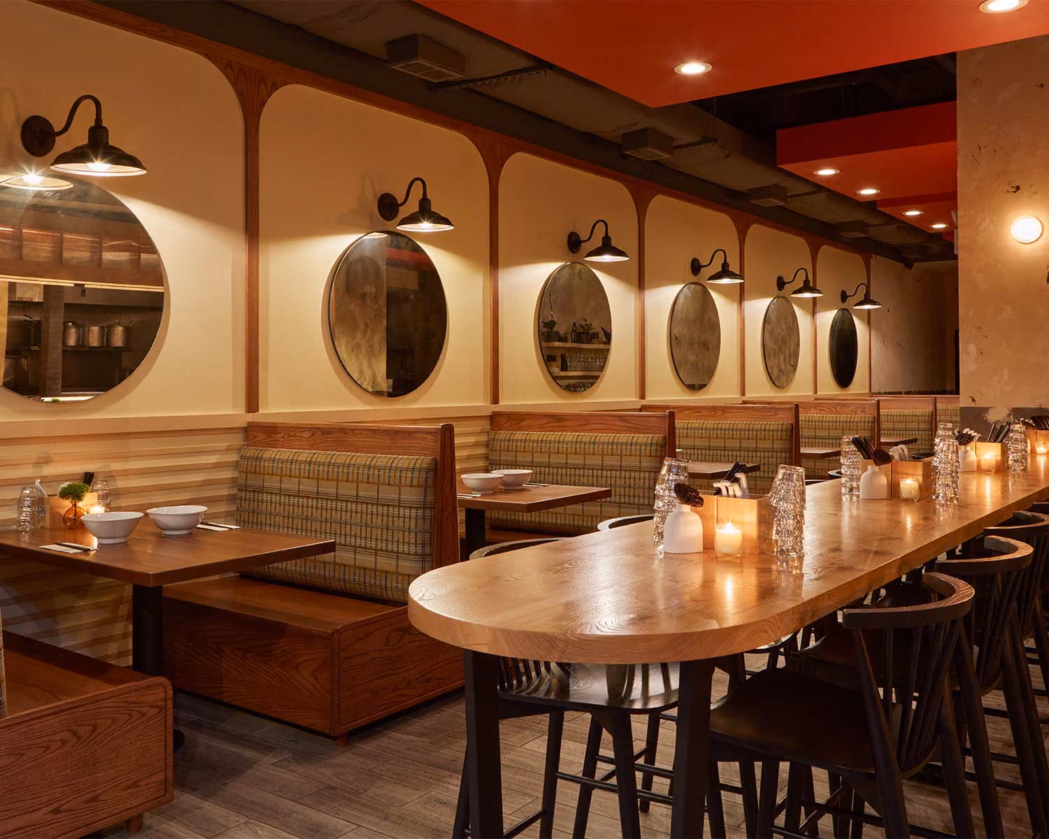 Akahoshi Ramen dining room with round mirrors, wall sconces, booth seating and a long wood counter
