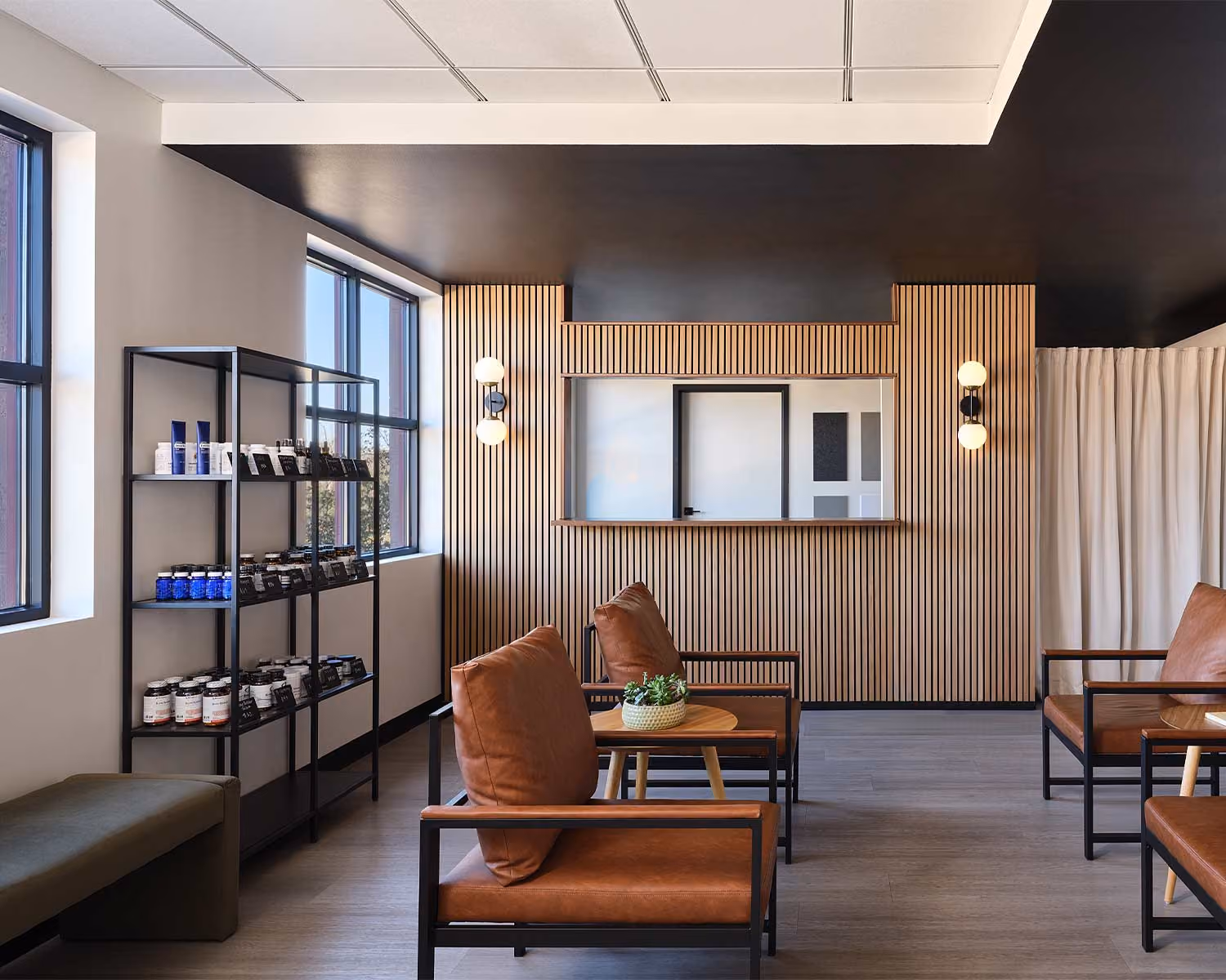 Elite Wellness lounge with leather chairs, a wood-slat wall and retail shelving