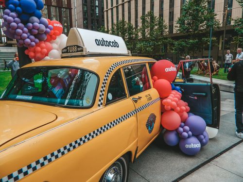 A taxi with balloons attached to the back of it.