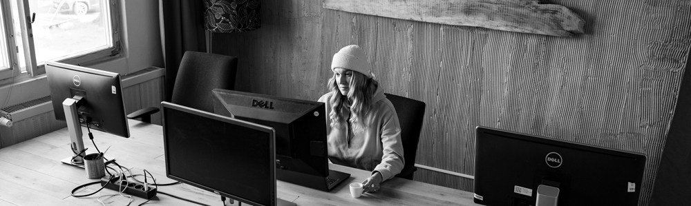 Shaper Liam Bulgen stojí ve své dílně, průhled na tenisové hřiště, surfboard na stole